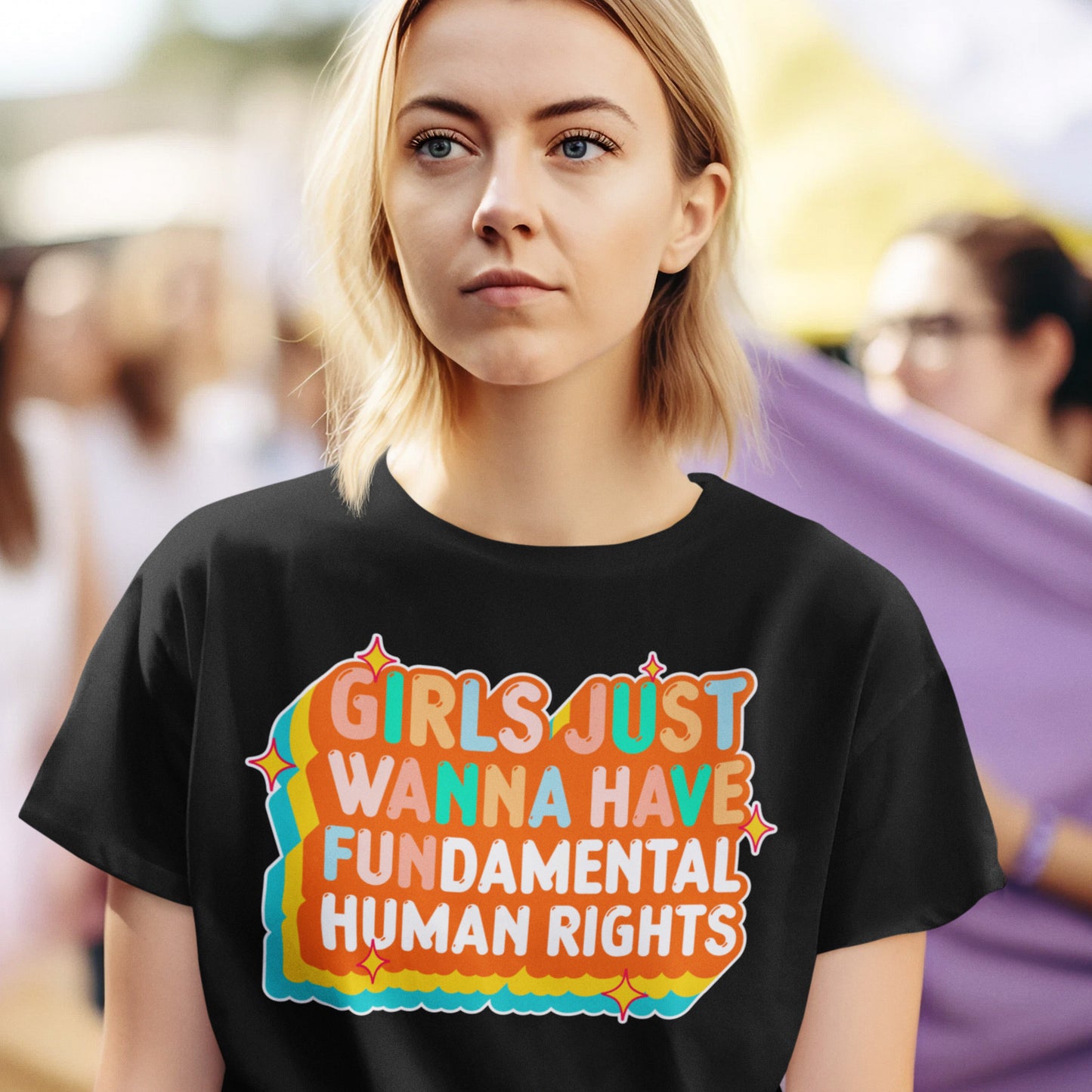 Model wearing the black “Girls Just Wanna Have Fundamental Human Rights” retro sunset design t-shirt in a casual streetwear look. Progressive fashion by Blue Wave USA.