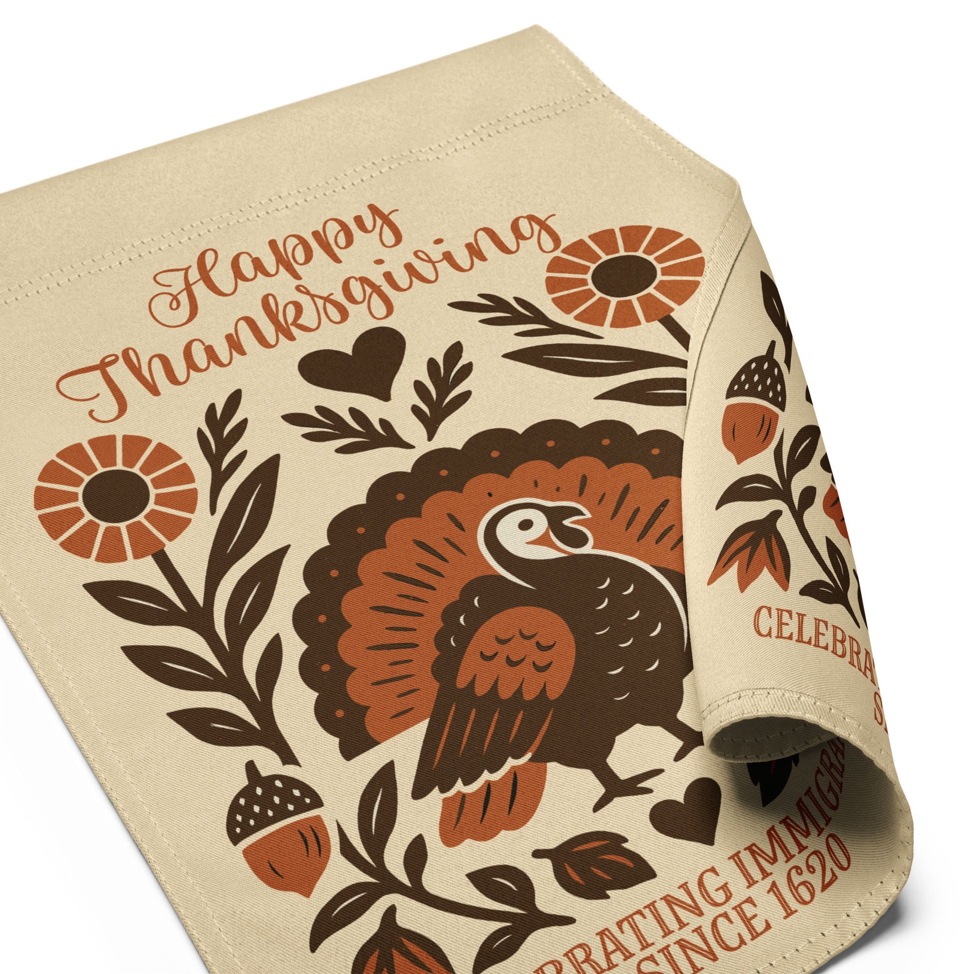 Angled view of the “Happy Thanksgiving – Celebrating Immigrants Since 1620” garden flag with curled fabric corner highlighting the folk-art turkey and floral elements.