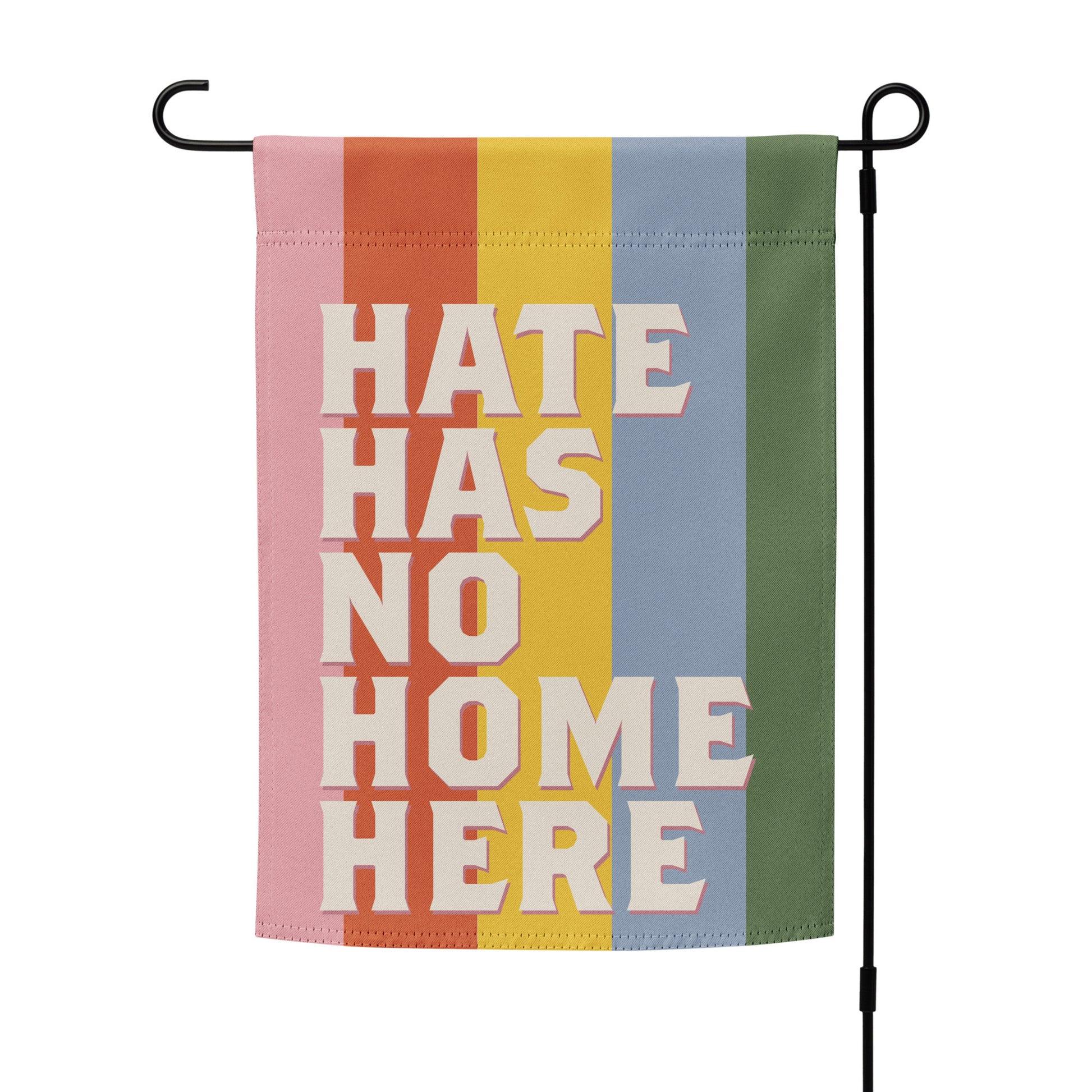 Progressive garden flag displayed on black metal stand featuring stacked retro typography and rainbow stripe background, social justice garden decor from Blue Wave USA.