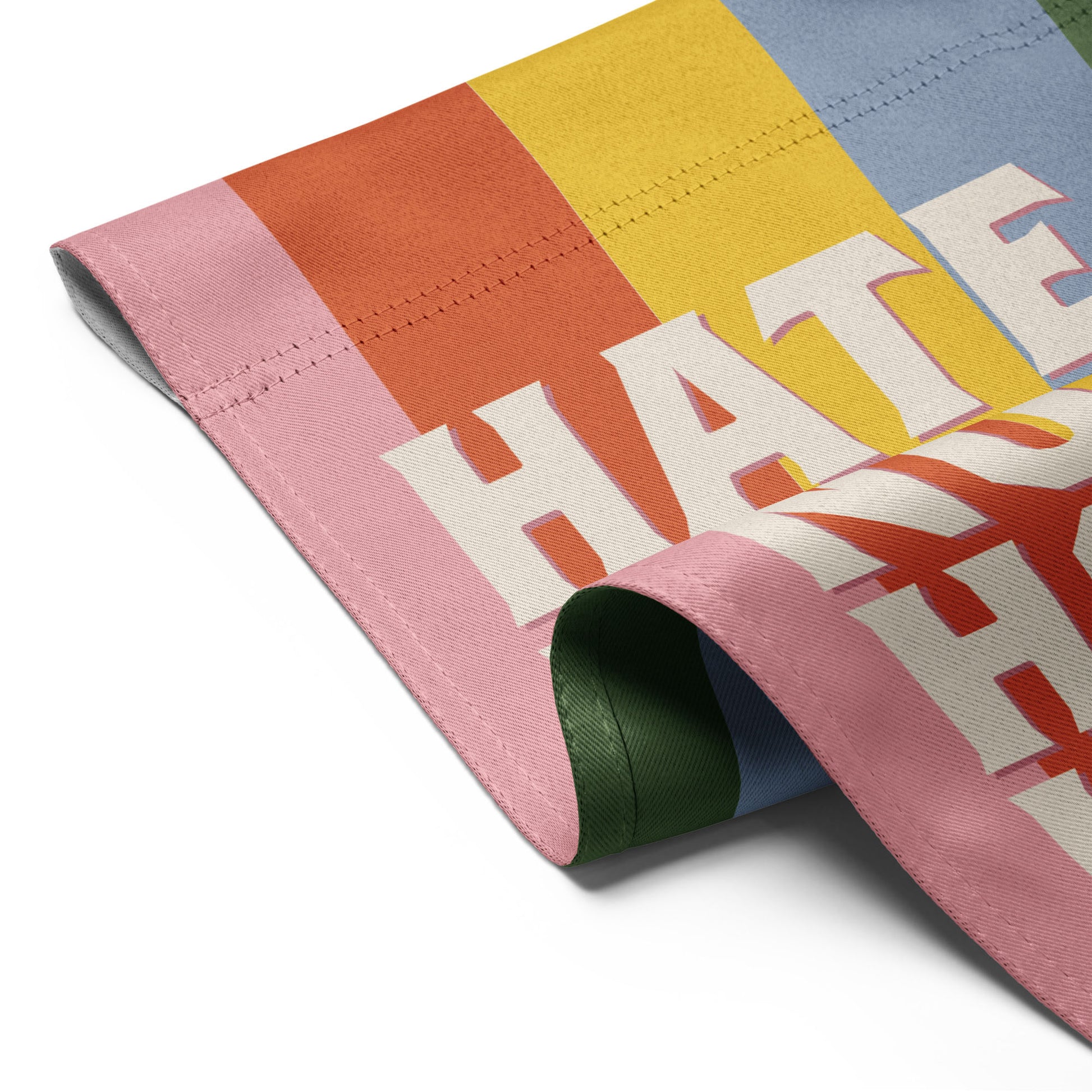 Detail view of progressive garden flag fabric fold showing rainbow stripe colors and retro typography, inclusive activist garden decor.