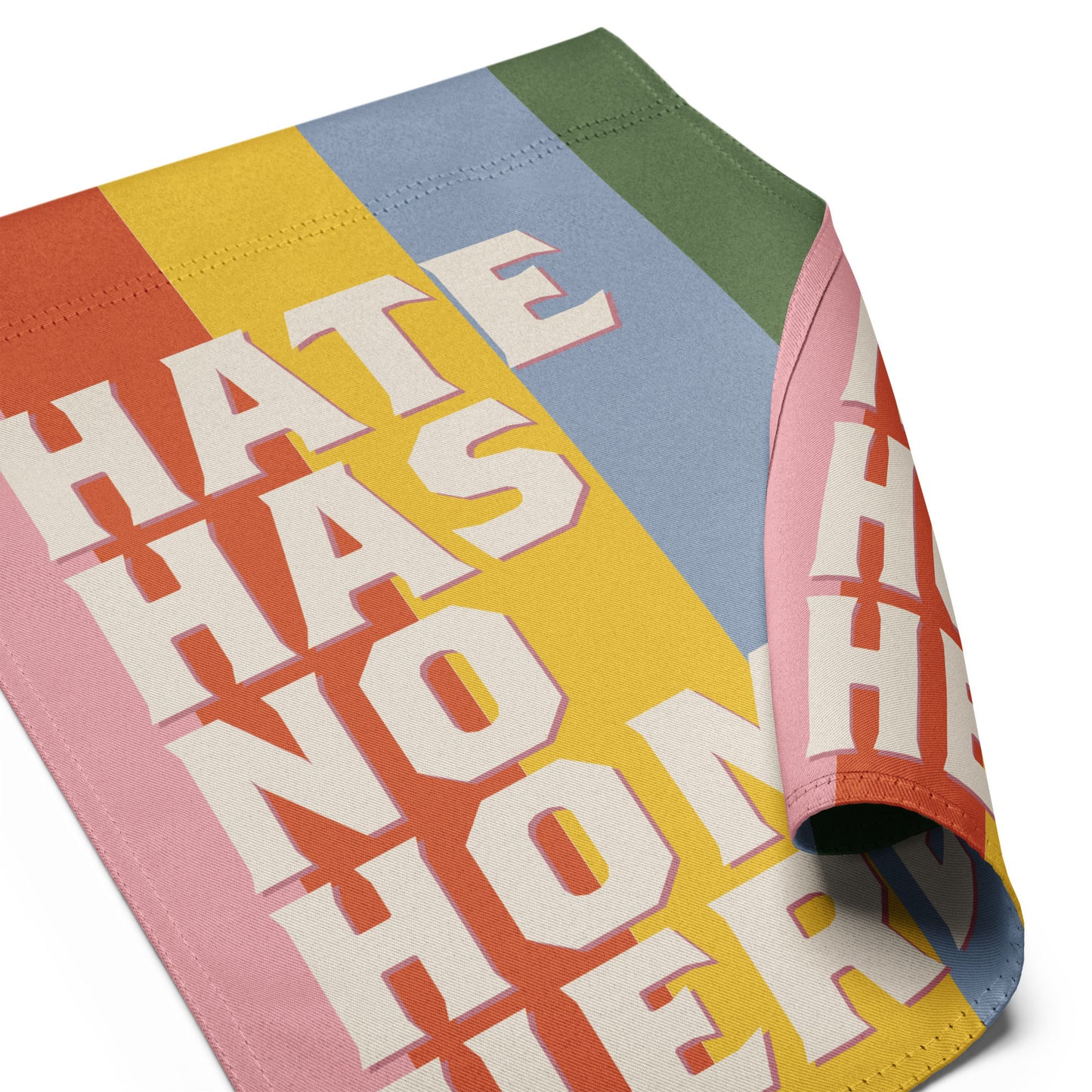 Close-up of progressive garden flag fabric showing retro stacked typography and rainbow stripe background, durable activist outdoor decor.