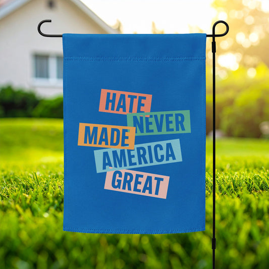Progressive garden flag featuring stacked typographic artwork and phrase “HATE NEVER MADE AMERICA GREAT,” blue background, outdoor display on metal garden flag stand.