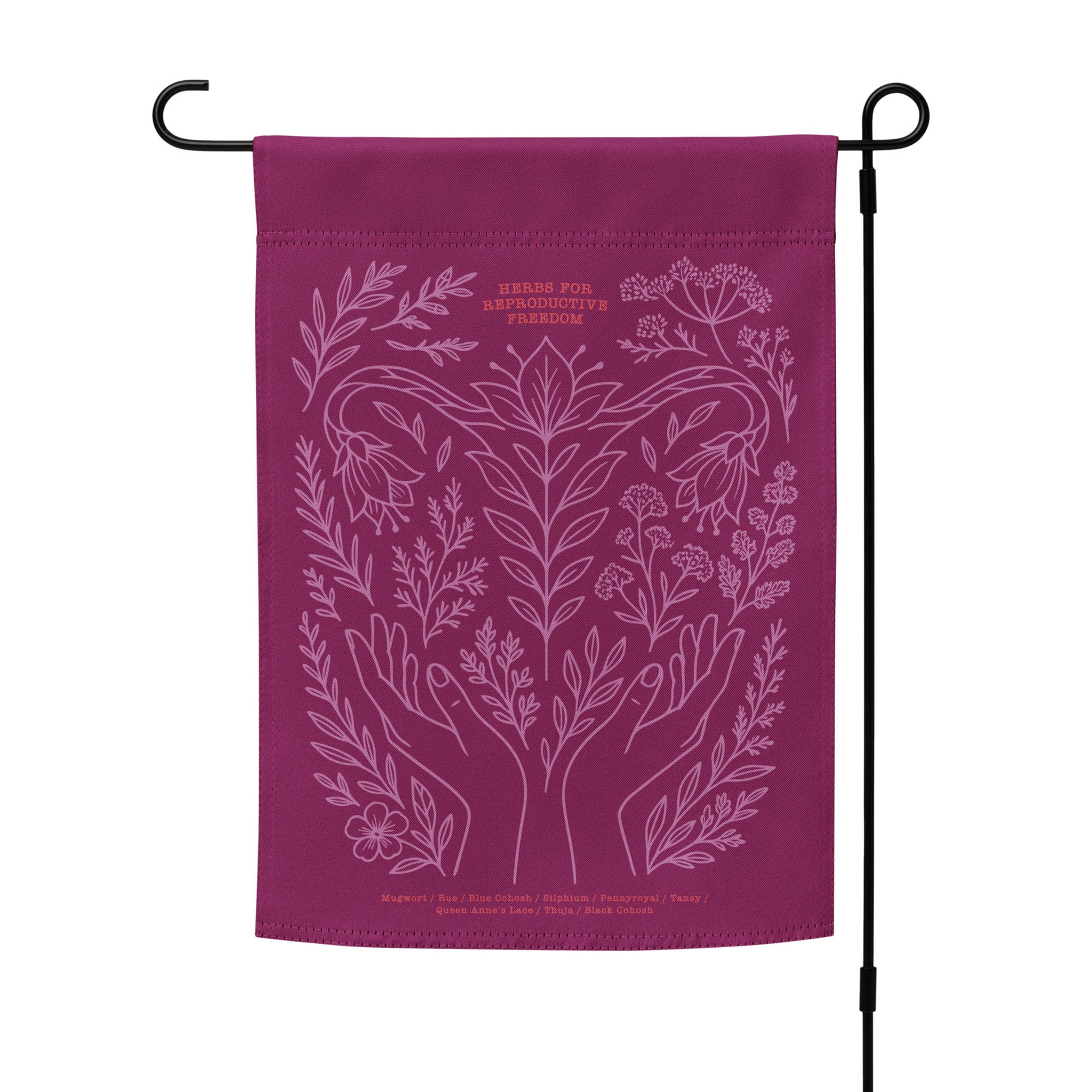 Magenta “Herbs for Reproductive Freedom” garden flag on outdoor flag stand, featuring hands, herbs, and moon motif — a bold pro-choice statement for your yard.