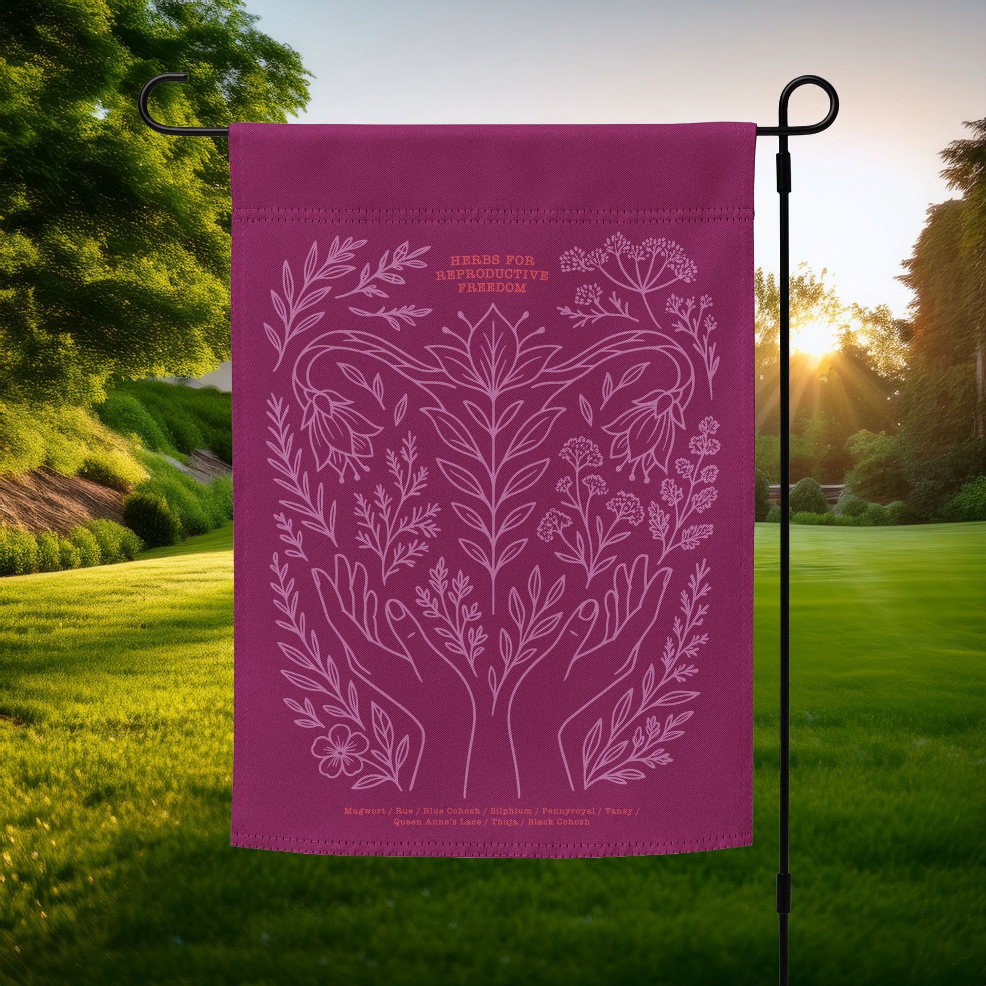Magenta garden flag featuring a pink botanical illustration of herbs, flowers, and hands with the phrase “Herbs for Reproductive Freedom.”