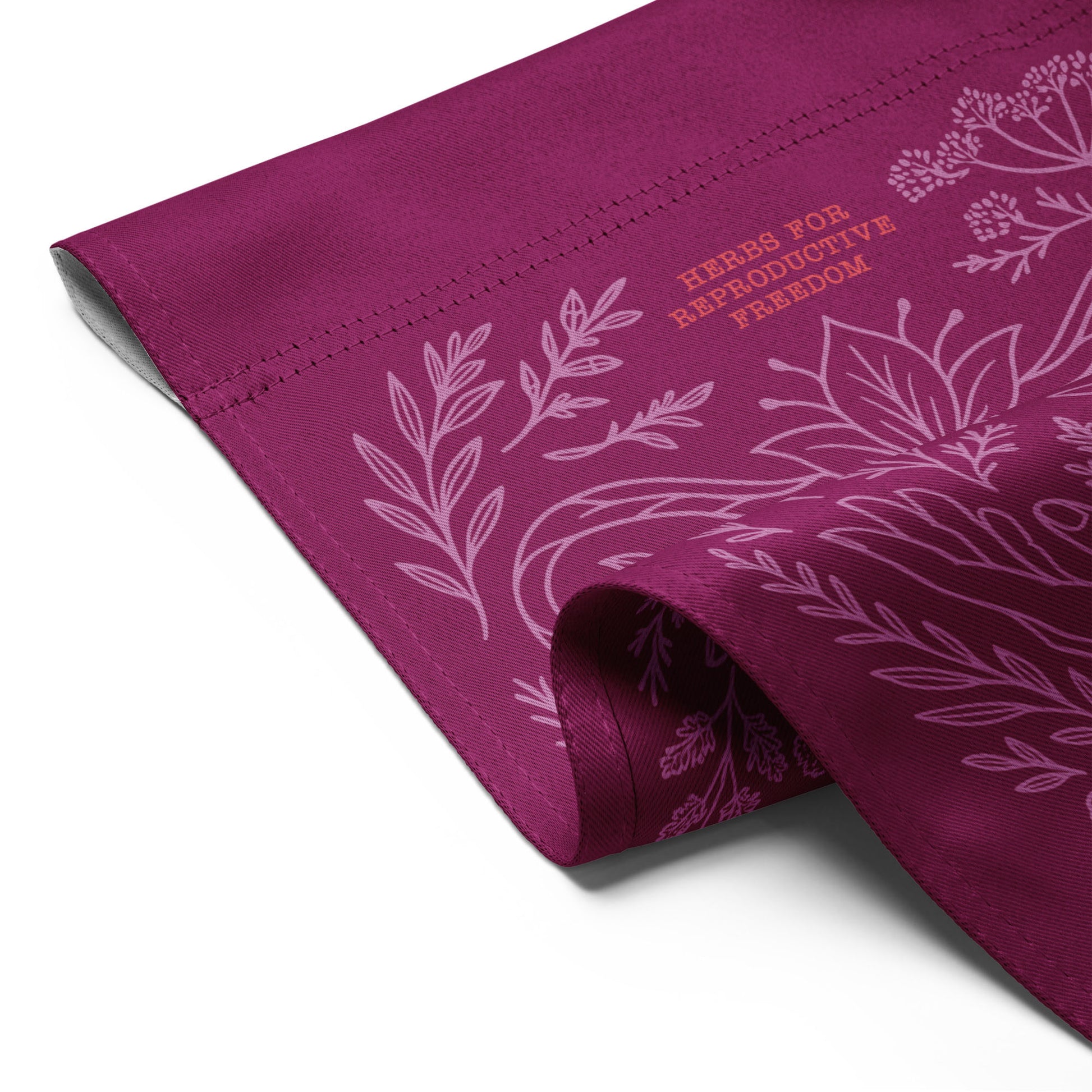Rolled magenta flag showing fabric texture and “Herbs for Reproductive Freedom” print in light pink line art. Eco-conscious flag by Blue Wave USA.