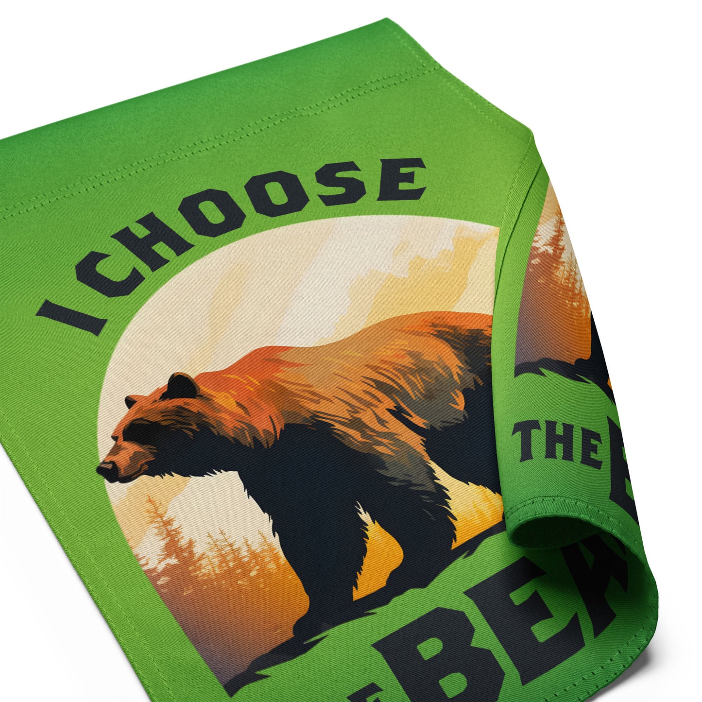 Close-up angled view of the garden flag fabric showing the bear illustration, sunset color gradient, and crisp typography spelling “I CHOOSE THE BEAR.”