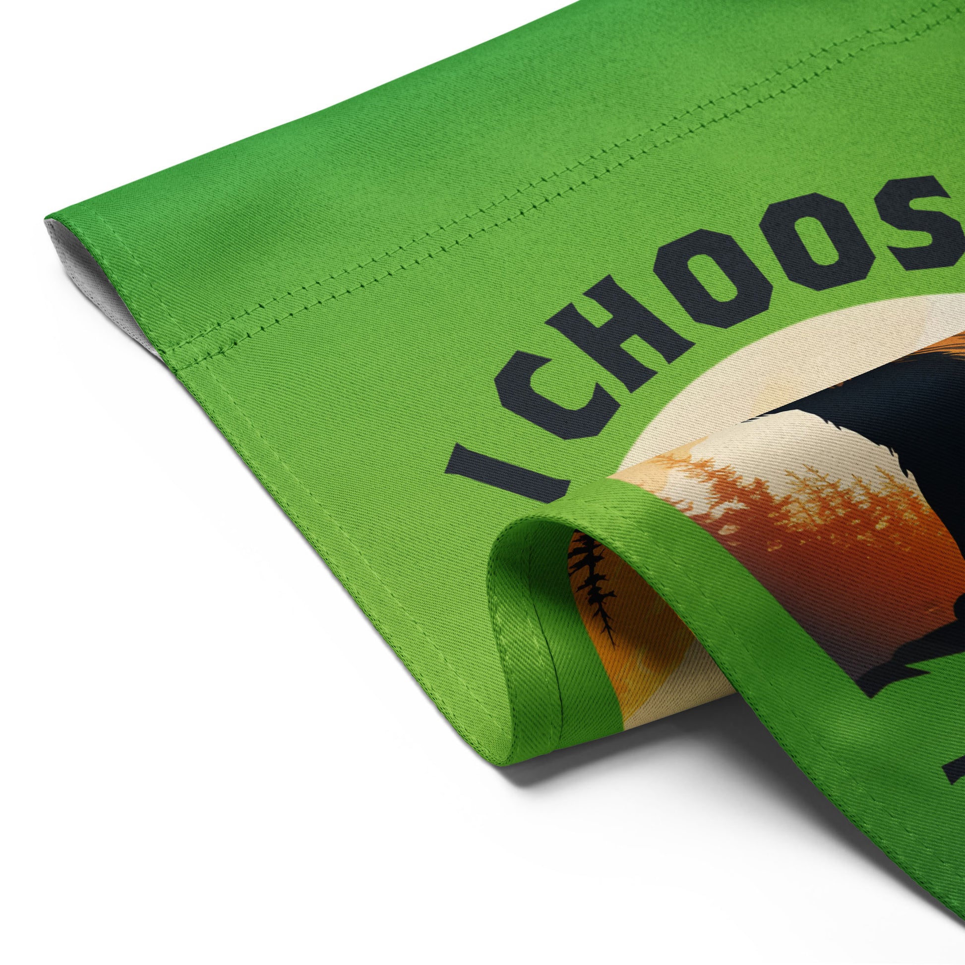 Folded green garden flag shown close up, revealing stitched edges, smooth fabric texture, and partial view of the bear illustration and text reading “I CHOOSE THE BEAR.”