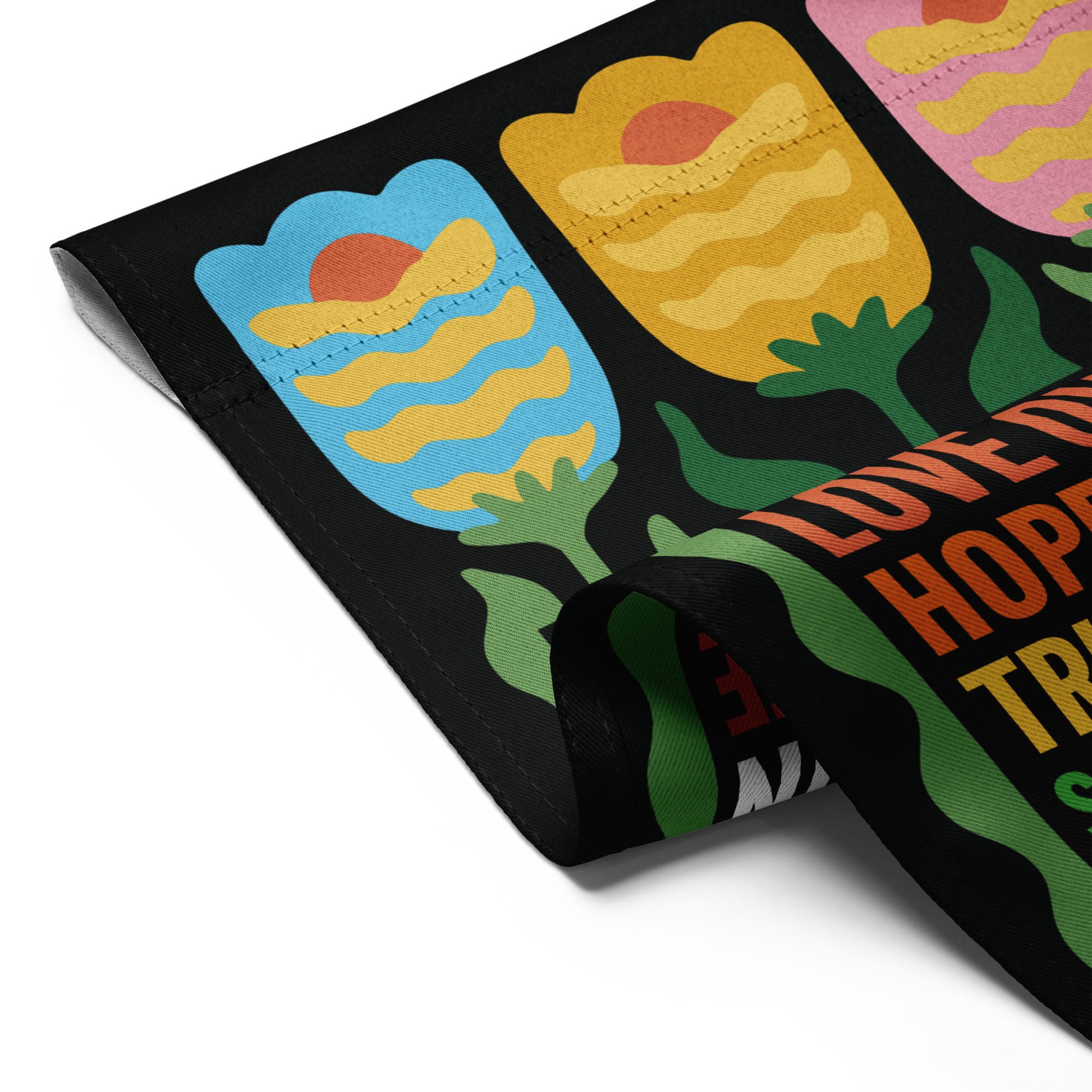 Folded black garden flag revealing repeated tulip motifs and the “In This House We Believe” design, progressive yard decor from Blue Wave USA.