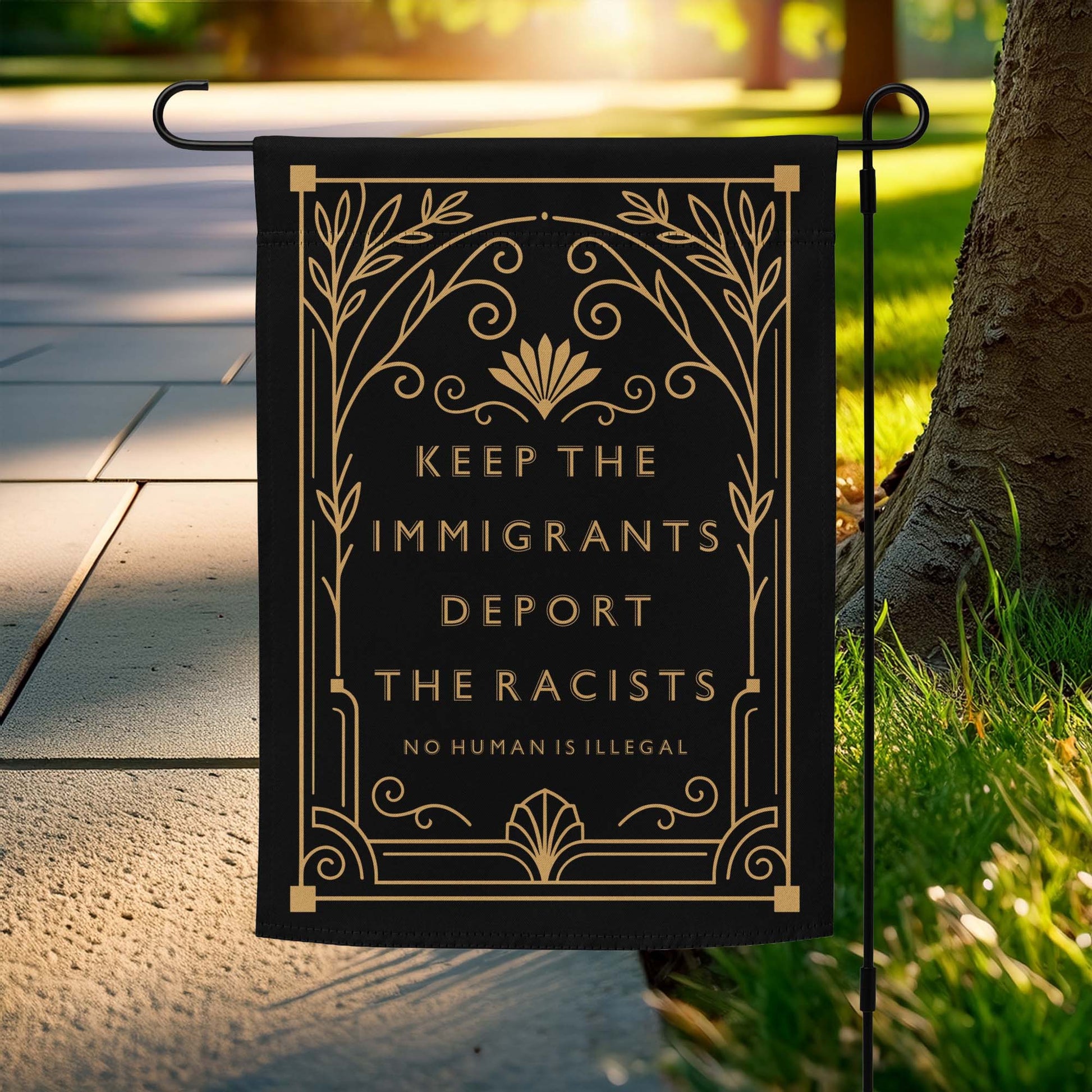 Keep The Immigrants Deport The Racists Garden Flag displayed on a stand outdoors.