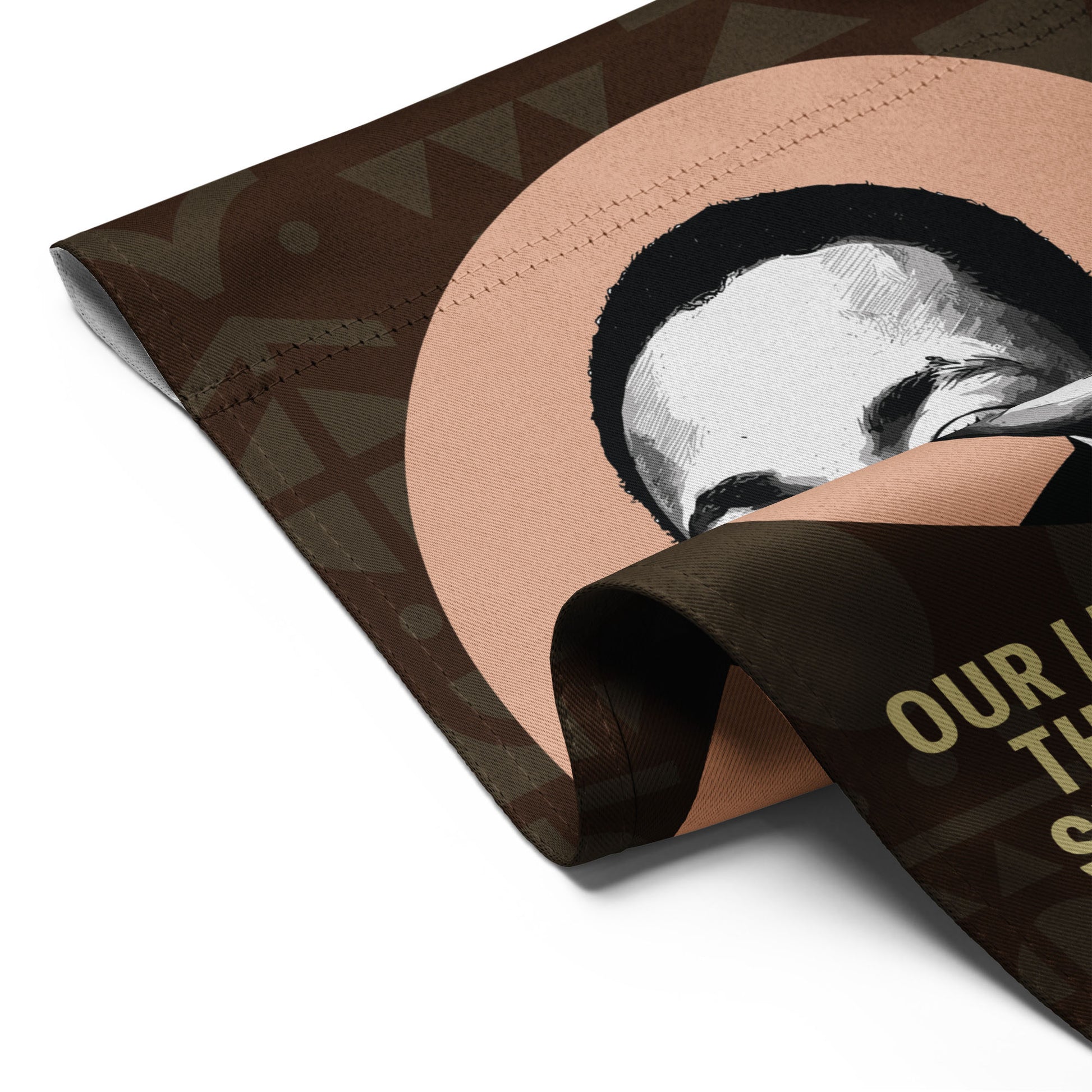 Close-up of MLK portrait garden flag showing stitched hem, folded fabric, and part of the quote “OUR LIVES BEGIN TO END…” highlighting print detail and durability.