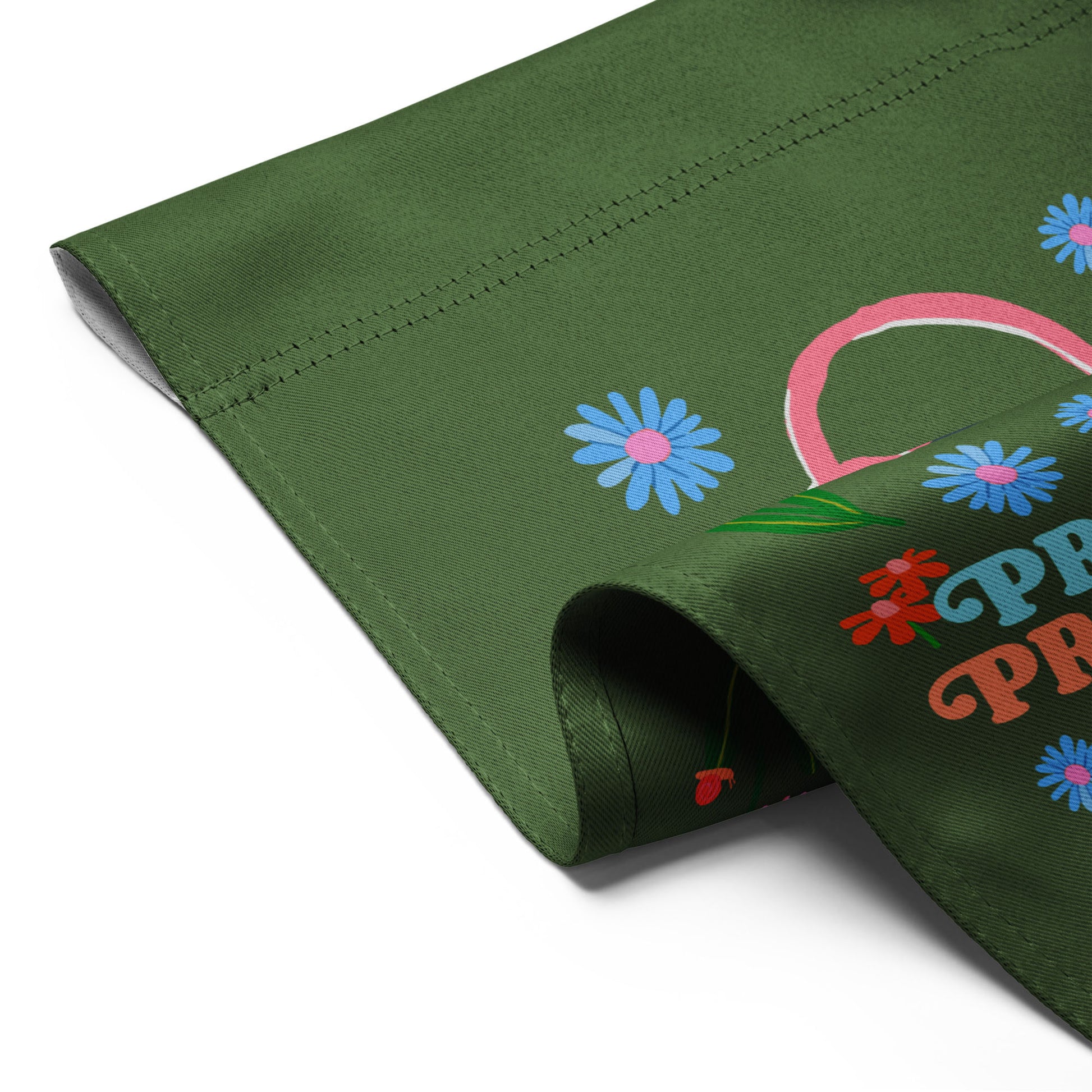Close-up of the green garden flag fabric showing stitched edges, smooth texture, and partial view of the pink cat and floral design with the phrase “PRO-CHOICE PRO-FEMINISM PRO-CATS.”