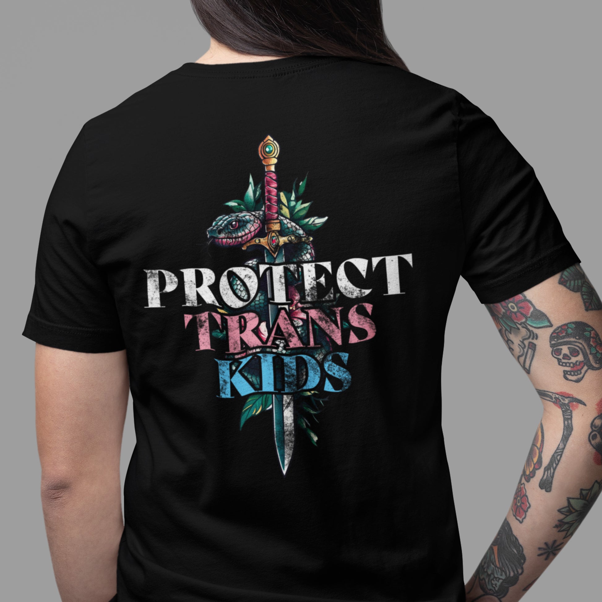Model wearing black unisex t-shirt showing large back graphic with snake wrapped around dagger and typography reading “Protect Trans Kids.”