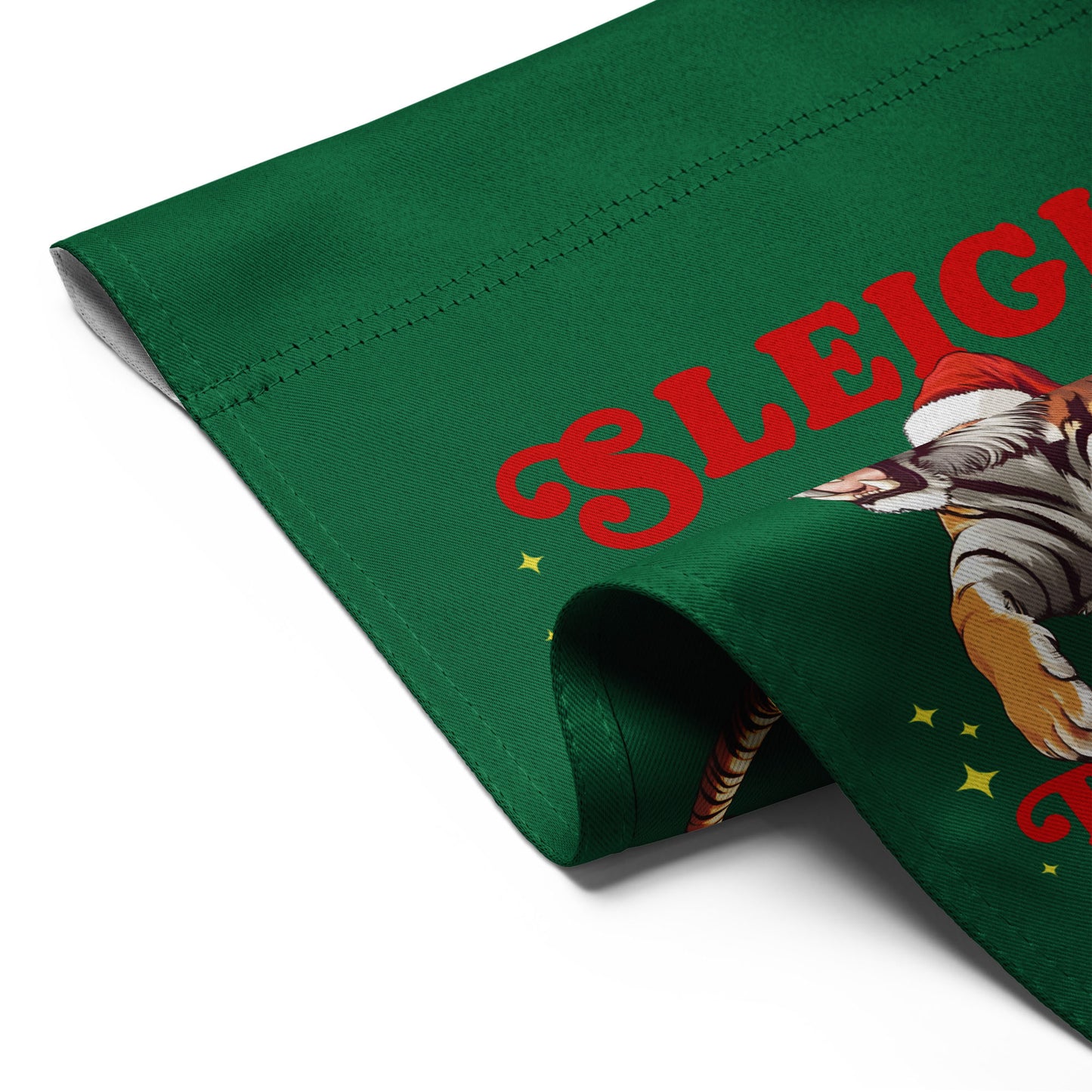 Close-up of green garden flag fabric with Santa riding tiger illustration and partial “Sleigh the Patriarchy” message showing print texture.