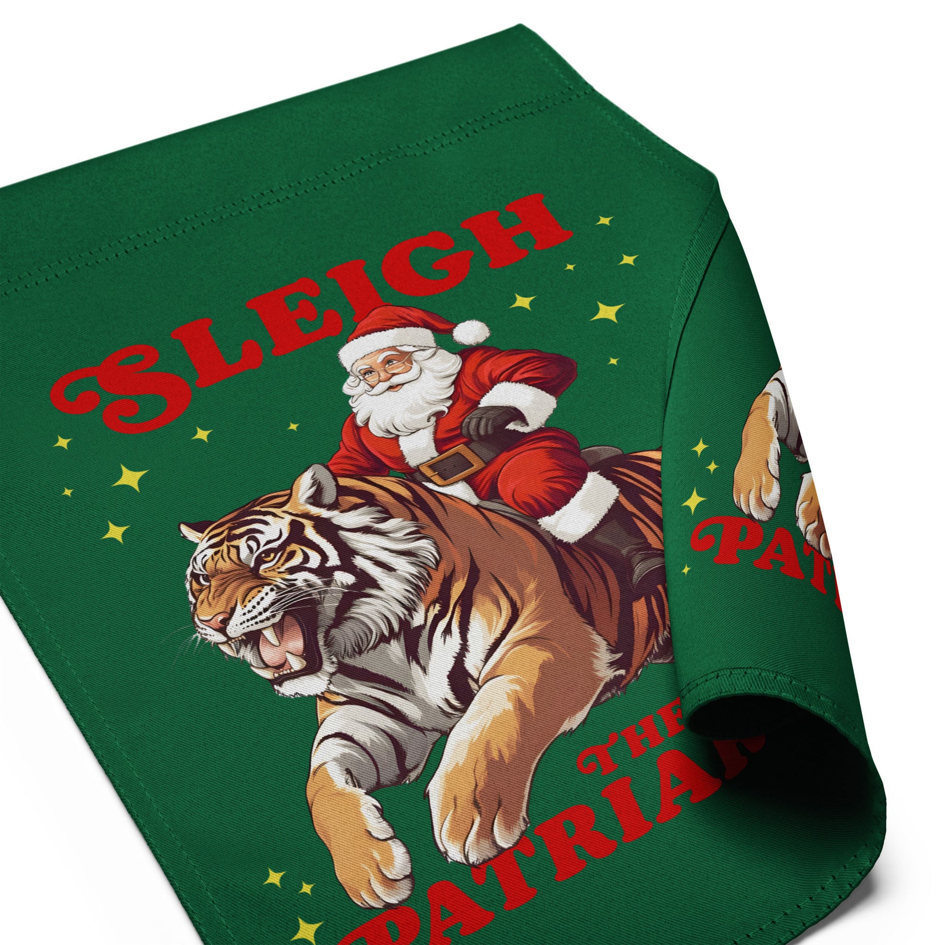 Angled view of green garden flag showing Santa riding tiger graphic with partial “Sleigh the Patriarchy” text and fabric drape detail.