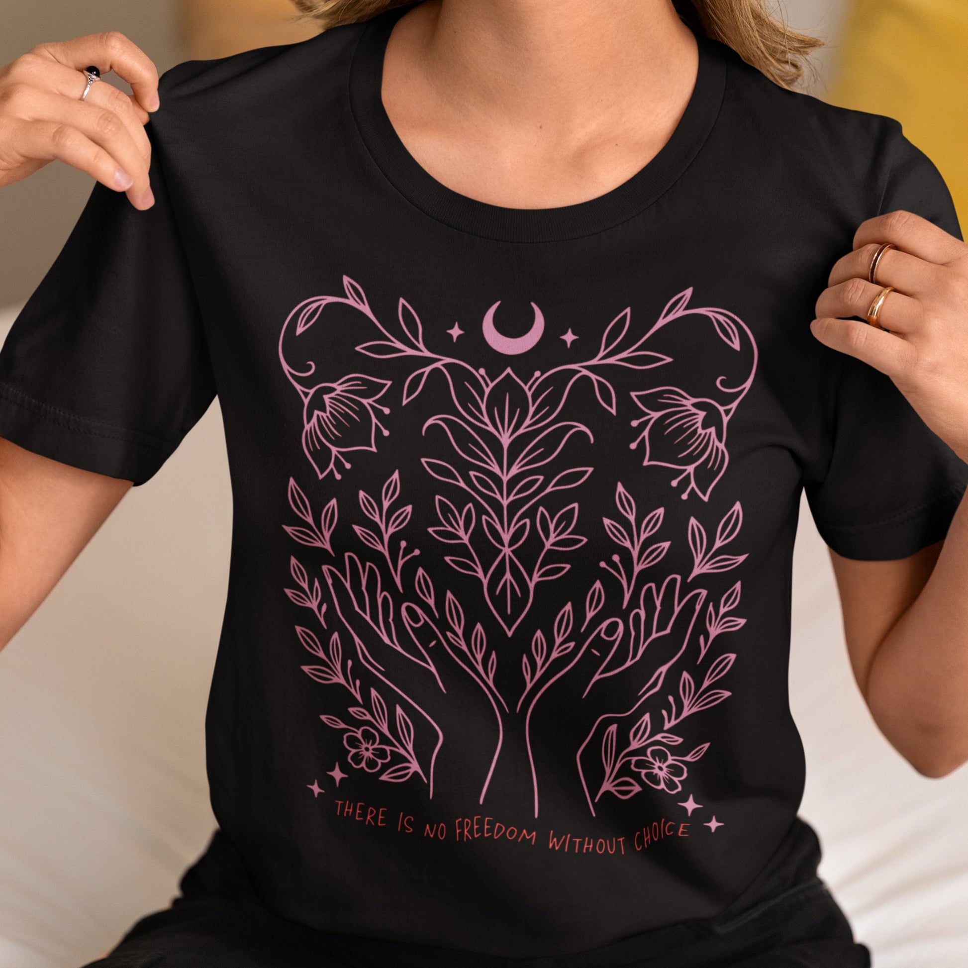 Model wearing the “There Is No Freedom Without Choice” black unisex t-shirt with pink botanical artwork. Feminist pro-choice tee by Blue Wave USA.