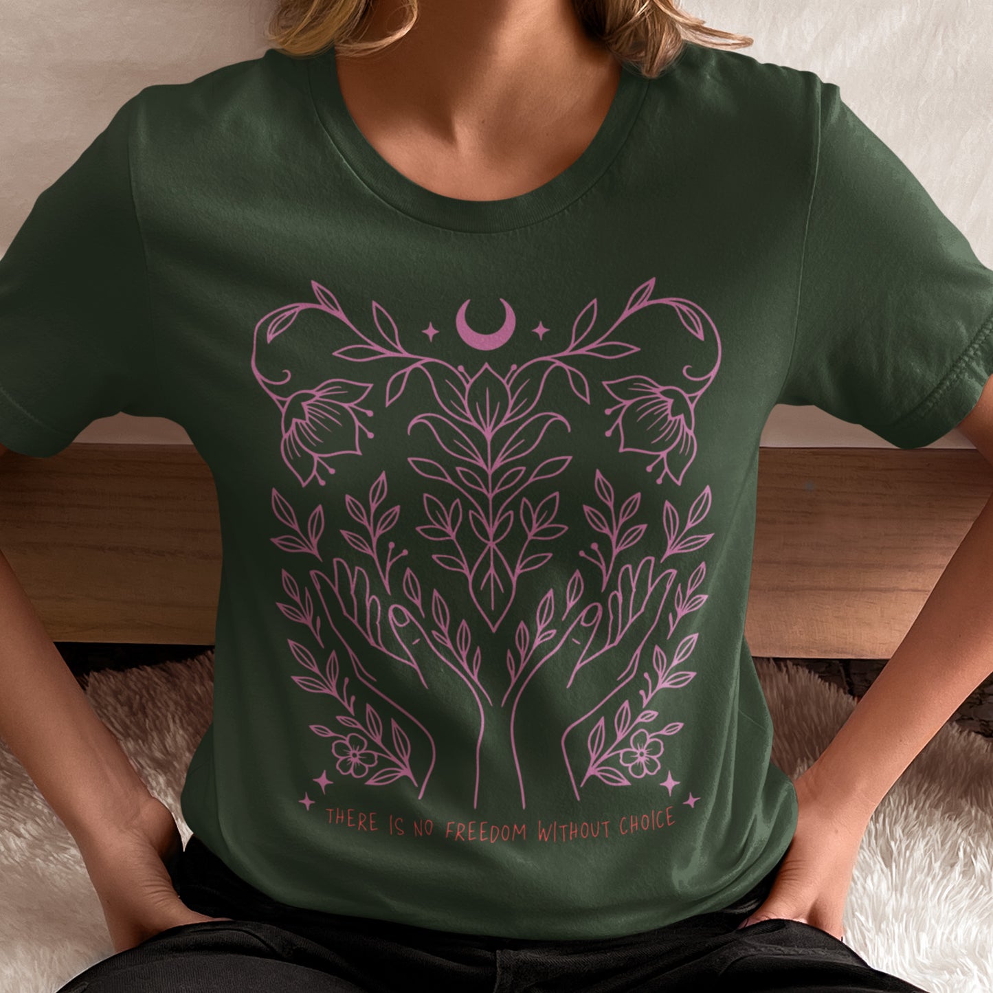 Model in forest green “There Is No Freedom Without Choice” shirt, featuring elegant pink botanical and celestial line art. Progressive reproductive rights design by Blue Wave USA.