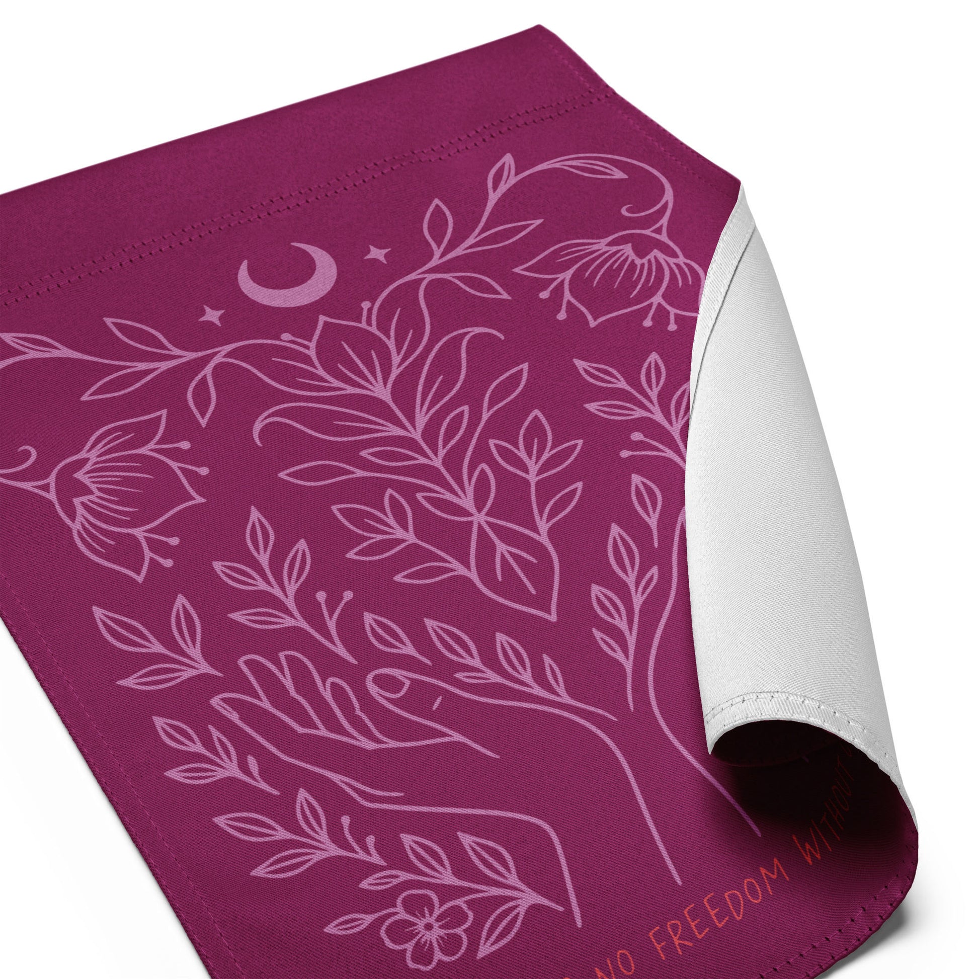 Close-up of the plum pro-choice garden flag with the corner rolled to show the white backing and detailed pink botanical illustration (hands, leaves, crescent moon) from the “There Is No Freedom Without Choice” design.