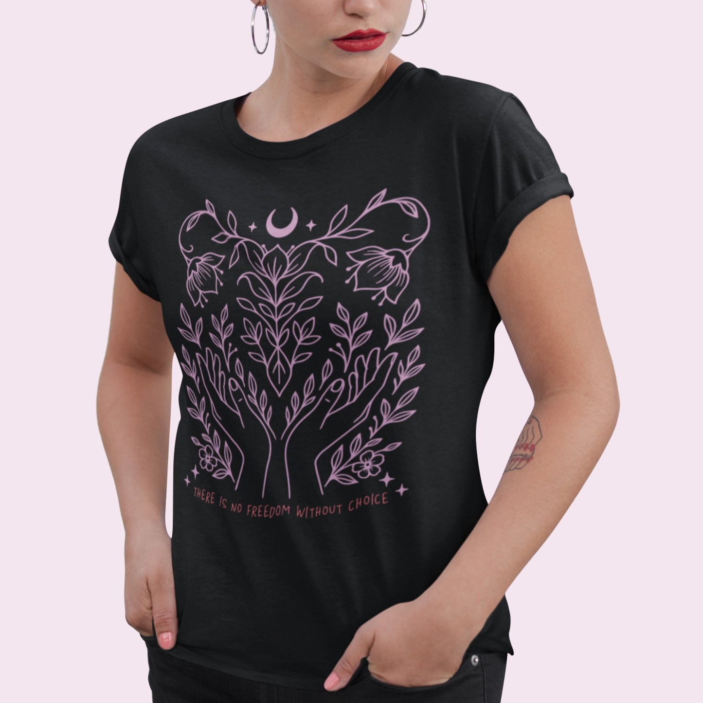 Model wearing the black “There Is No Freedom Without Choice” relaxed-fit tee, featuring intertwined vines, stars, and the moon in pastel pink. Ethical and empowering apparel by Blue Wave USA.
