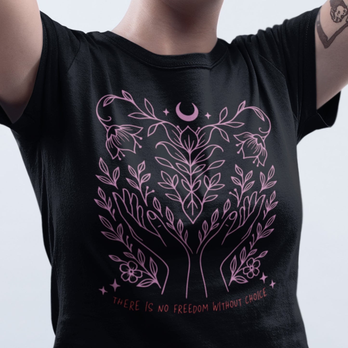 Close-up of model wearing the “There Is No Freedom Without Choice” women’s t-shirt in black with soft pink botanical design. Feminist pro-choice tee by Blue Wave USA.
