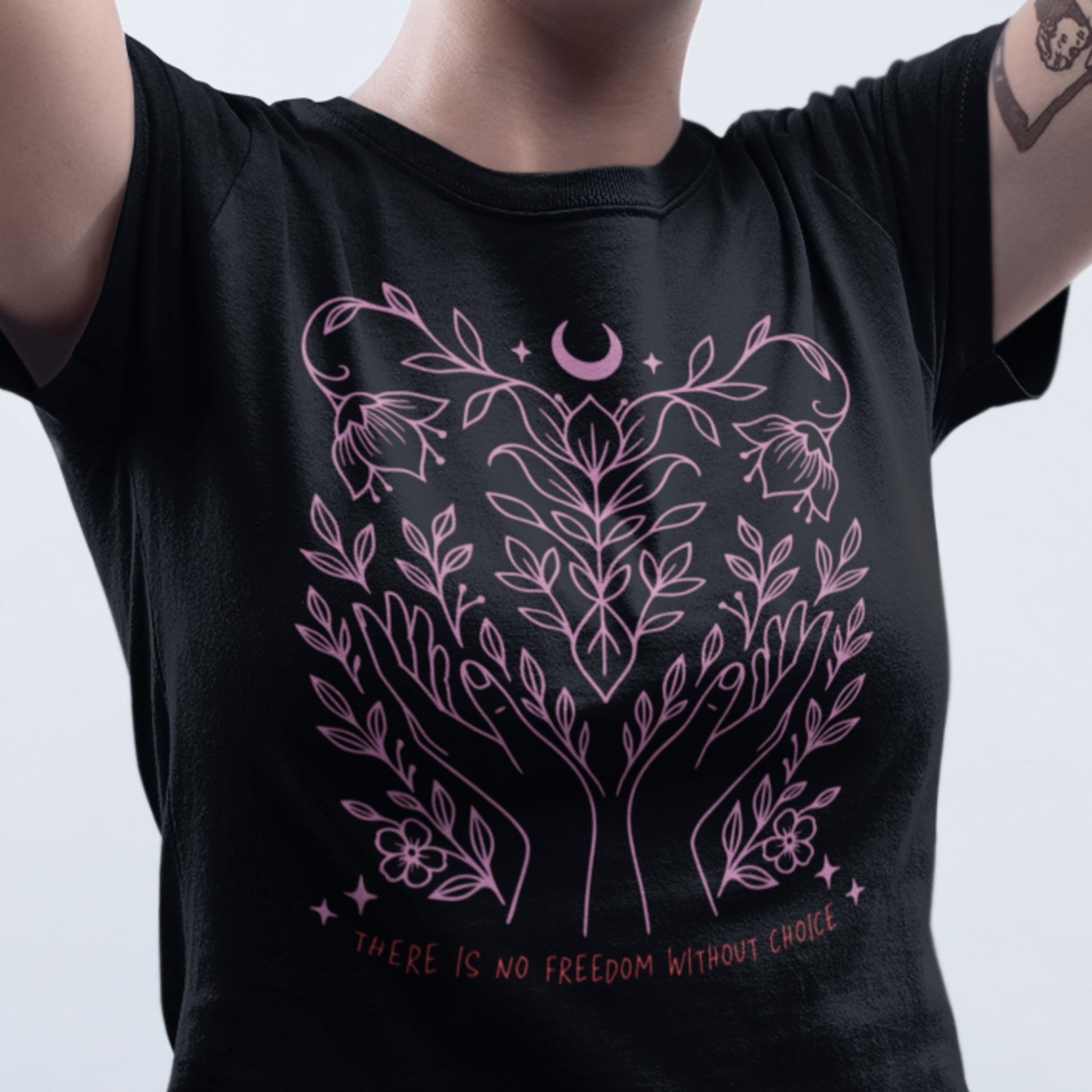 Close-up of model wearing the “There Is No Freedom Without Choice” women’s t-shirt in black with soft pink botanical design. Feminist pro-choice tee by Blue Wave USA.