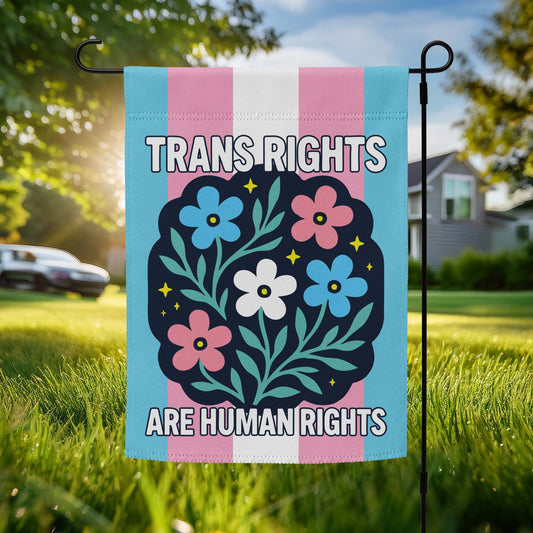 Garden flag with trans pride stripes and a floral wreath reading “Trans Rights Are Human Rights.”
