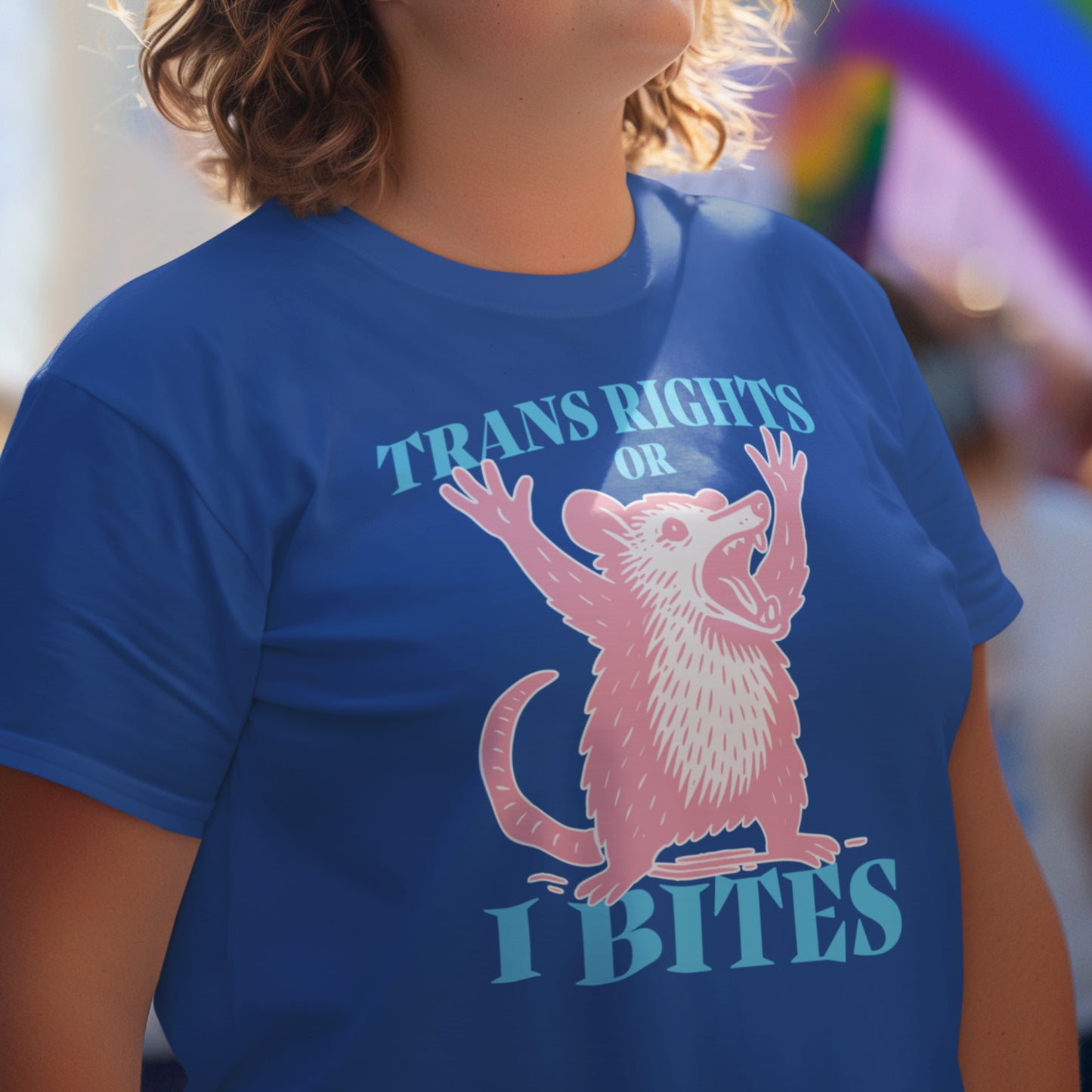 Person wearing blue “Trans Rights or I Bites” shirt, featuring a cute illustrated opossum and pride-forward message.