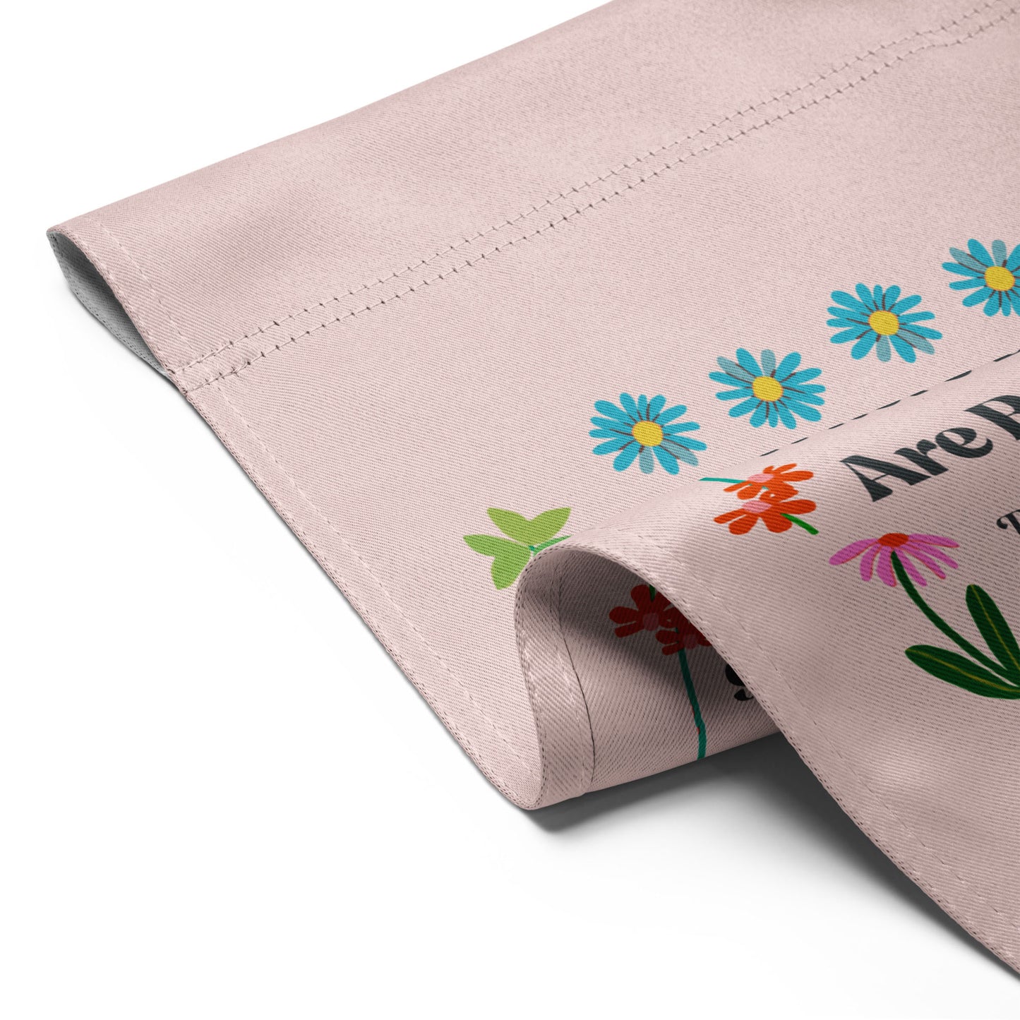 Close-up of the garden flag fabric edge, showing stitched hem, soft canvas texture, and partial view of the floral border and RBG quote text.