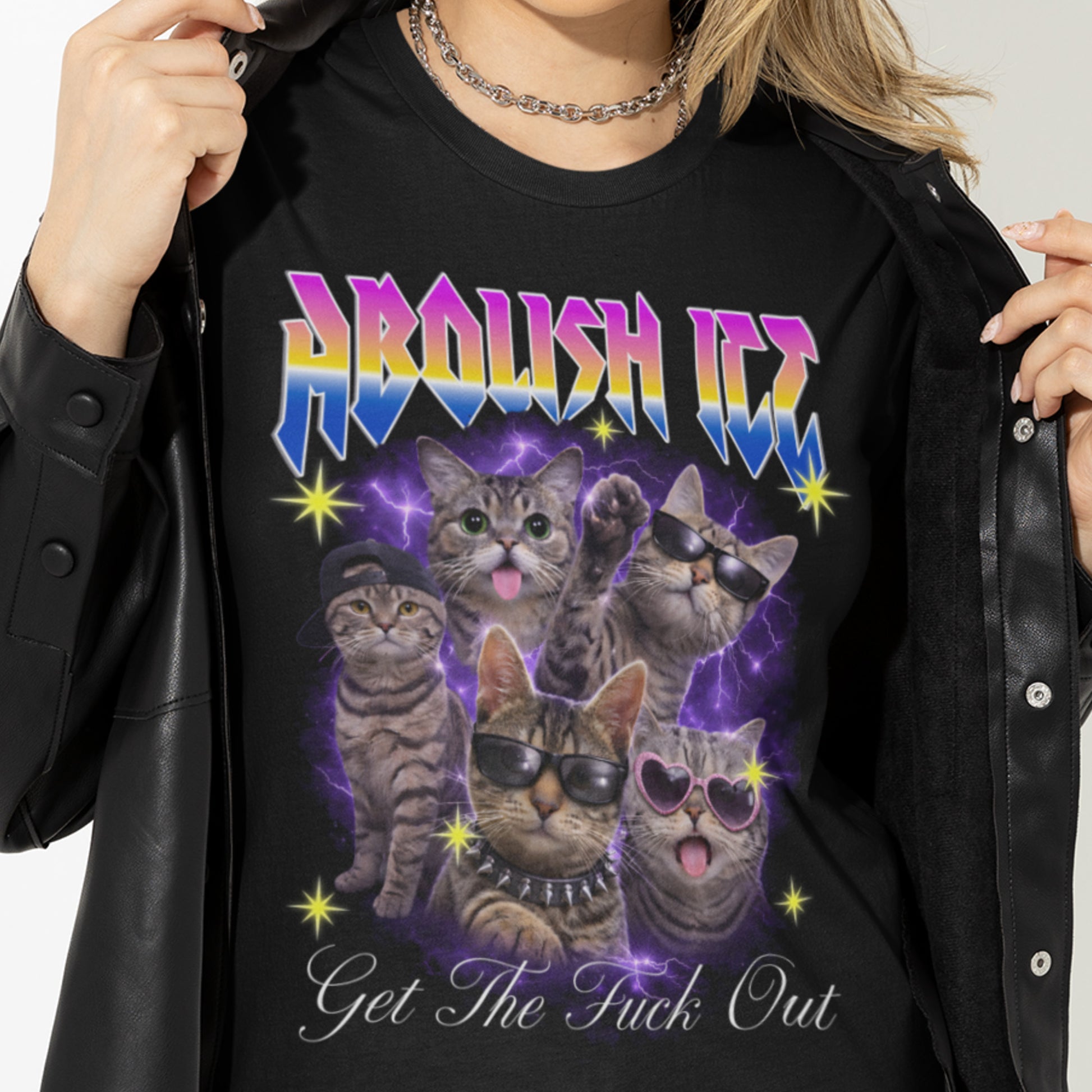 Model wearing black unisex t-shirt partially unzipped jacket revealing bootleg cat illustration with lightning, rainbow “ABOLISH ICE” text, and “Get The Fuck Out” below.