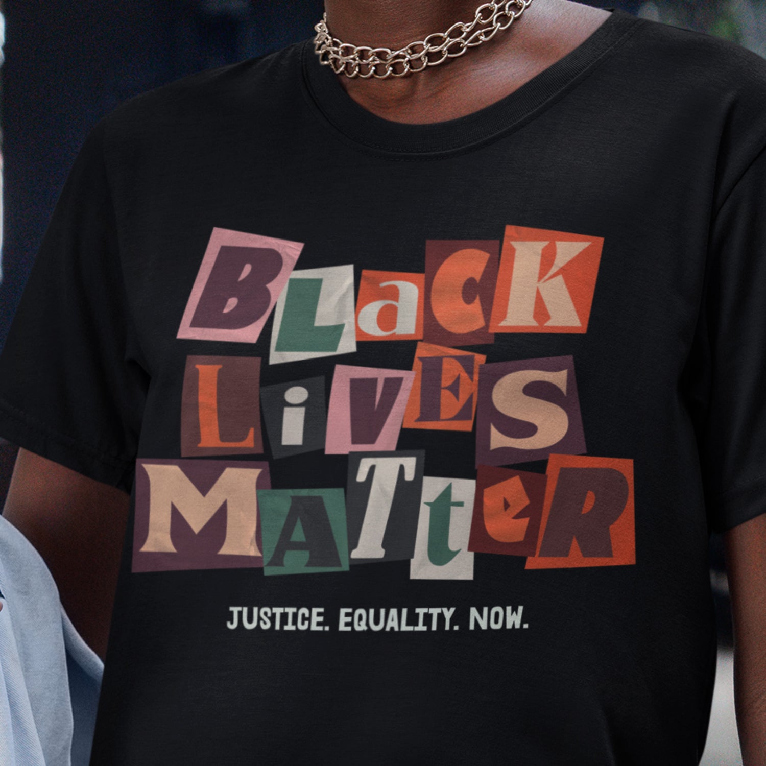 Close-up of a person wearing the black Black Lives Matter collage tee, showing the layered paper-style lettering that adds movement and urgency. A signature design from Blue Wave USA that turns art into resistance.