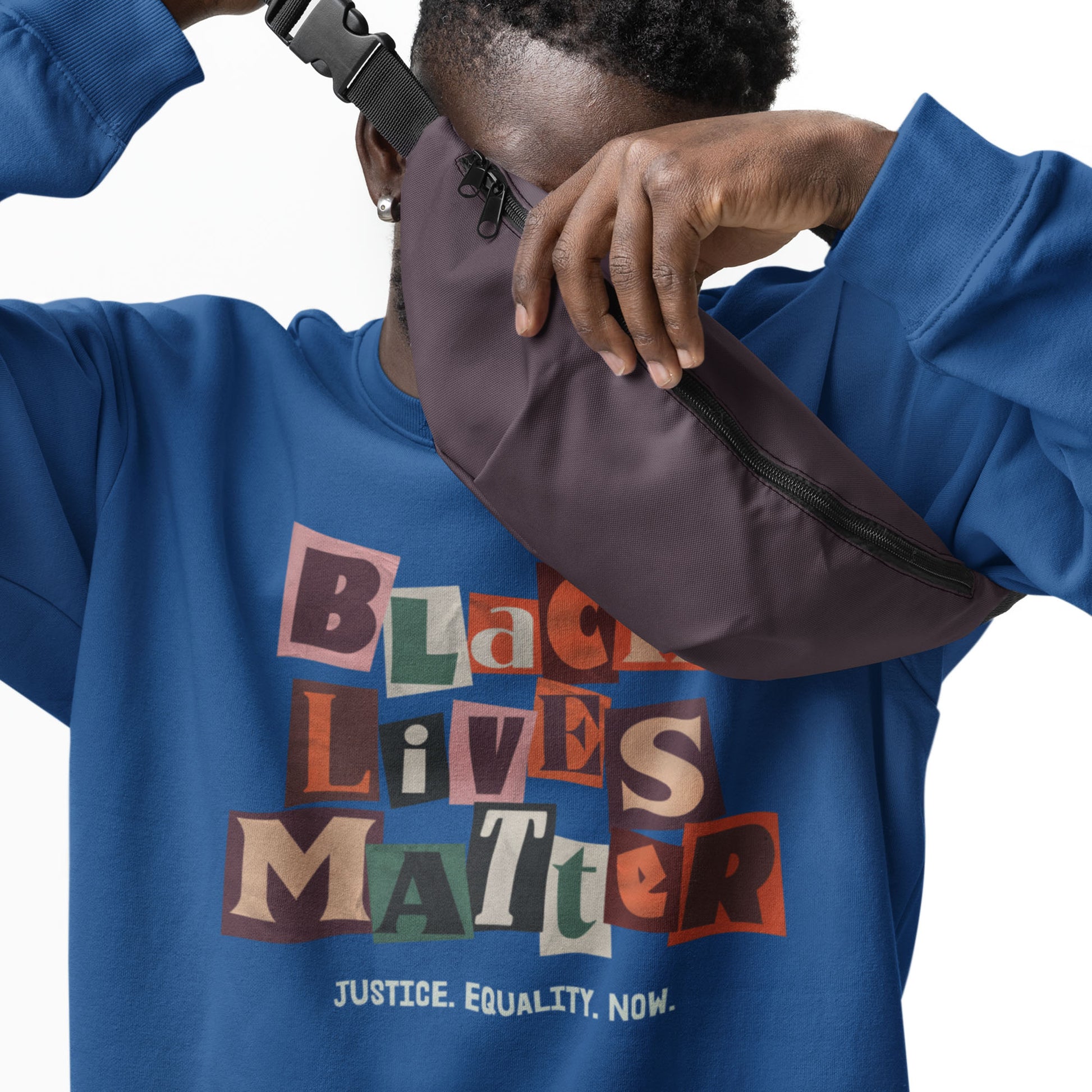 Person wearing a blue unisex premium sweatshirt with the vibrant collage-style “BLACK LIVES MATTER” lettering and “JUSTICE. EQUALITY. NOW.” message, framed in bold activist design.