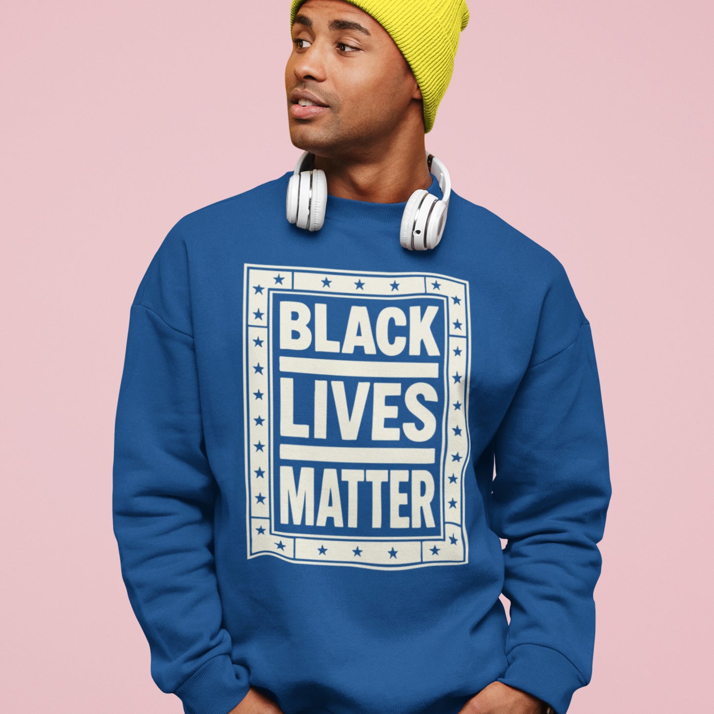 Person wearing a royal-blue unisex premium sweatshirt featuring the framed cream “BLACK LIVES MATTER” design with star accents, a bold everyday justice-focused piece.