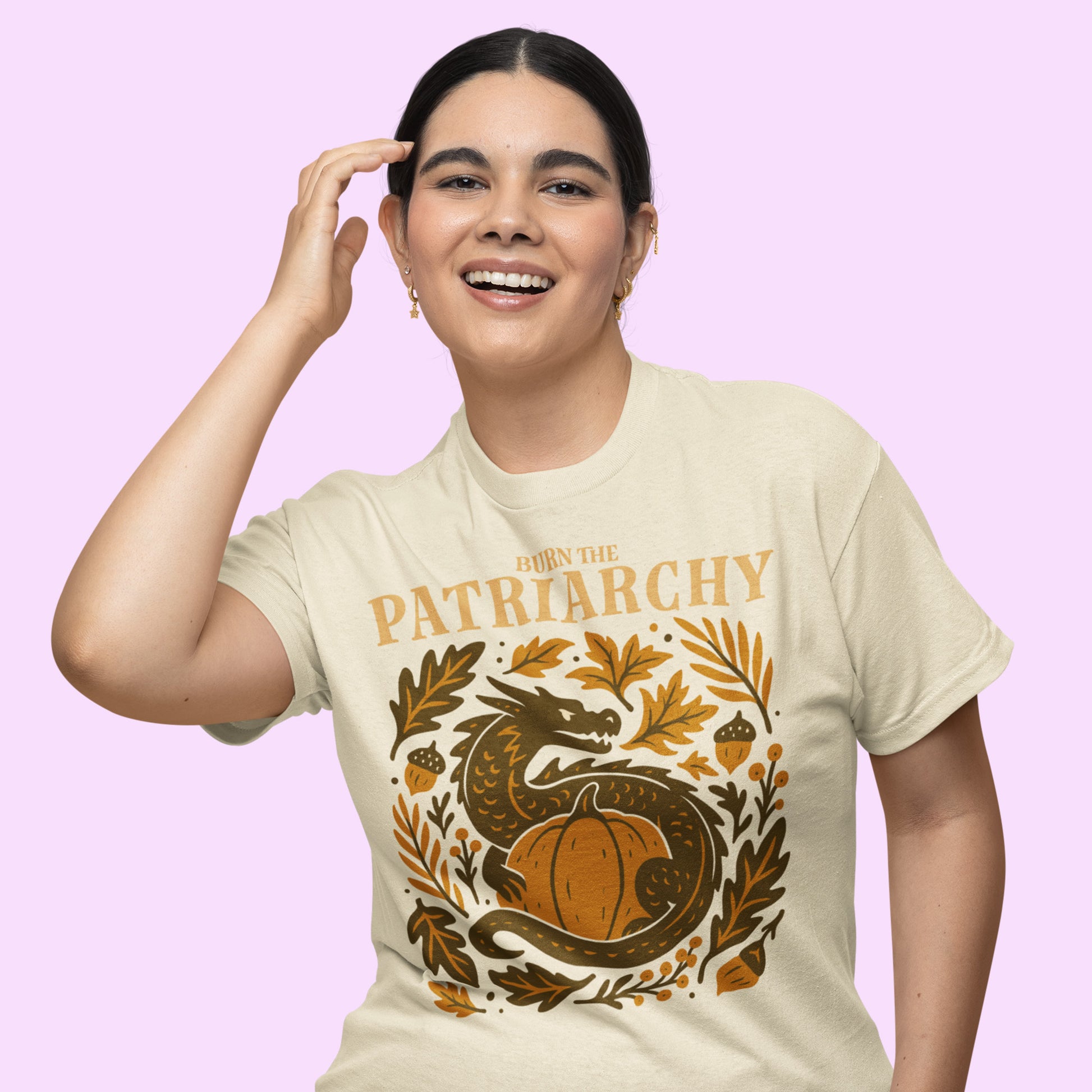 Smiling model in cream “Burn the Patriarchy” feminism dragon t-shirt, cozy autumn activist apparel with retro harvest tones.