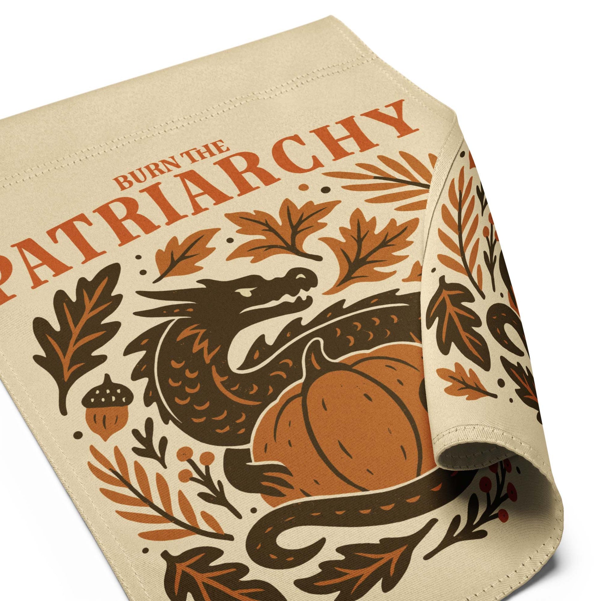 Folded corner close-up of “Burn the Patriarchy” dragon and botanical design printed on linen-textured garden flag fabric.