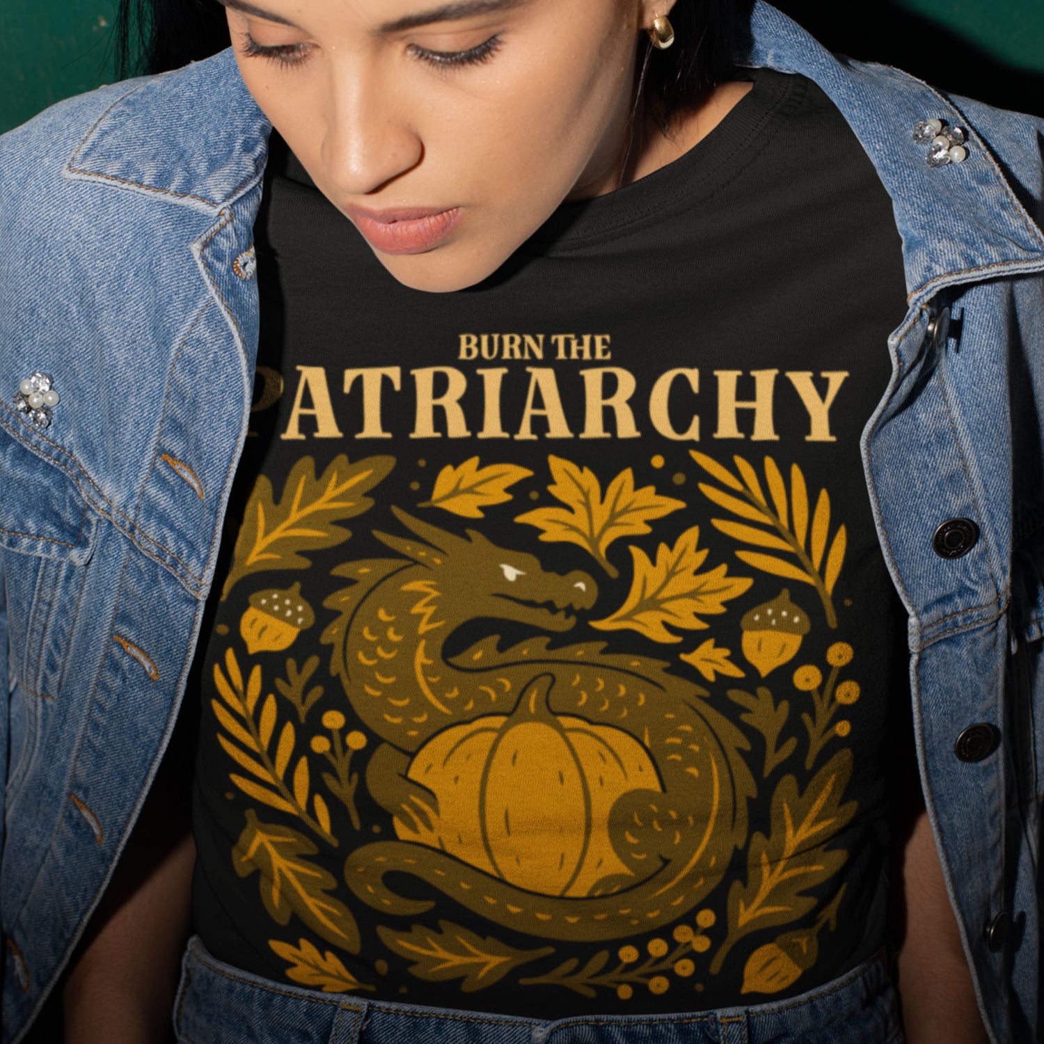 Model wearing “Burn the Patriarchy” dragon feminist shirt, Blue Wave USA progressive fall apparel with golden pumpkin design.