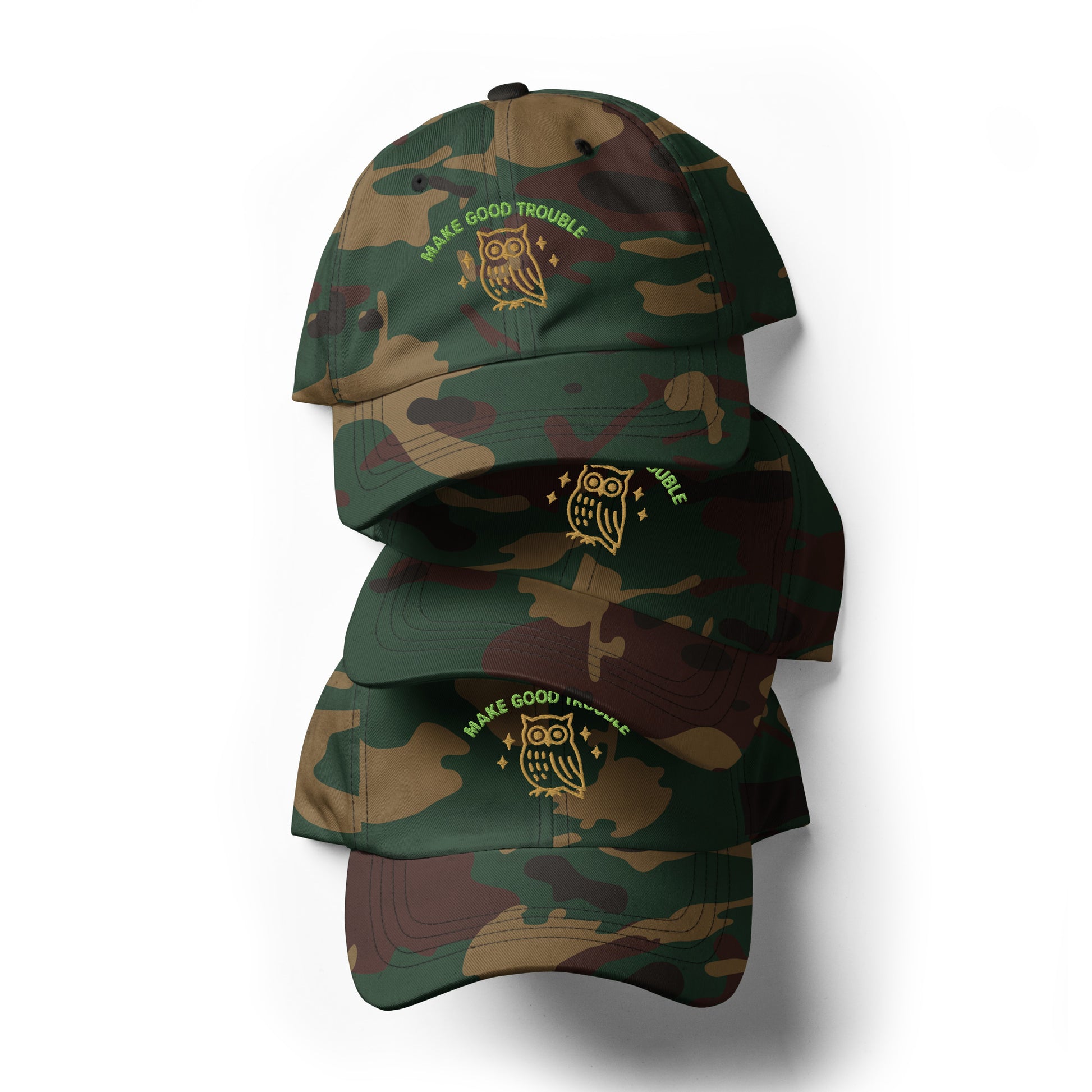 Stack of Make Good Trouble hats featuring owl and embroidered civil rights message - Green Camo