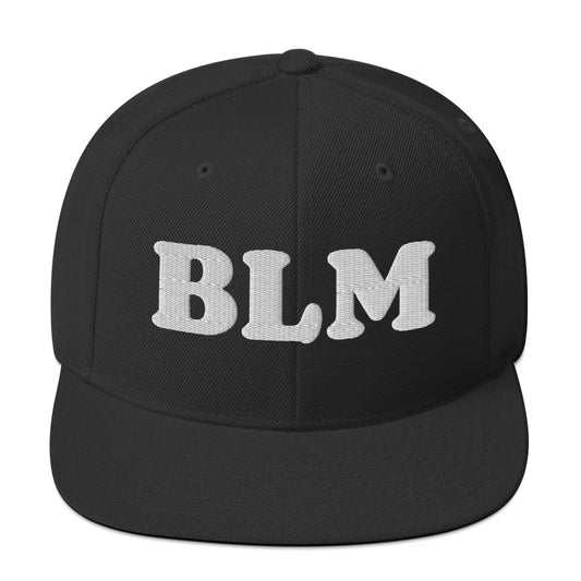 Black snapback hat with raised embroidered lettering reading “BLM,” bold minimalist design in tonal black thread on structured crown, flat brim style.