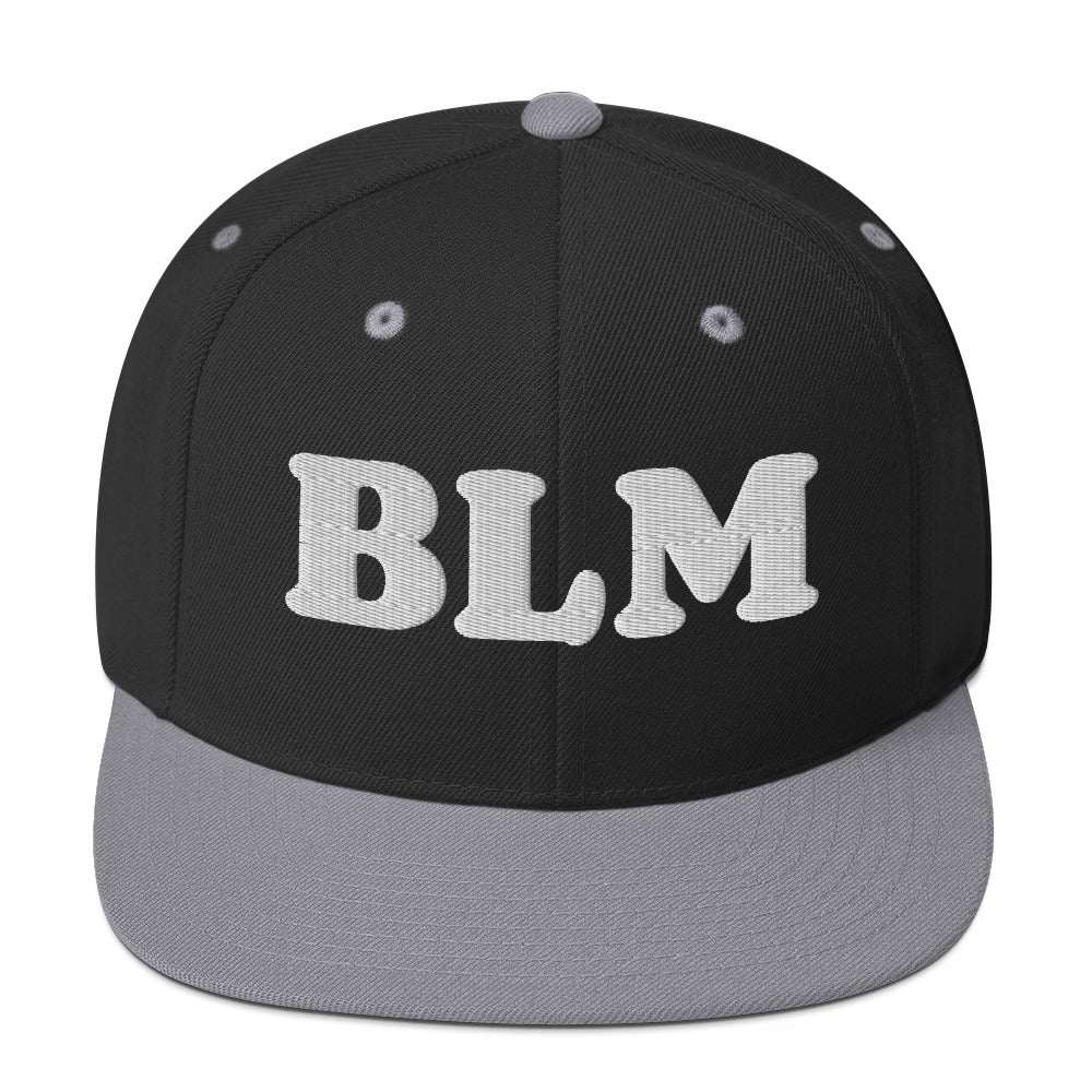 Black snapback hat with gray brim and raised embroidered “BLM” text, clean two-tone design shown from a front-facing angle.