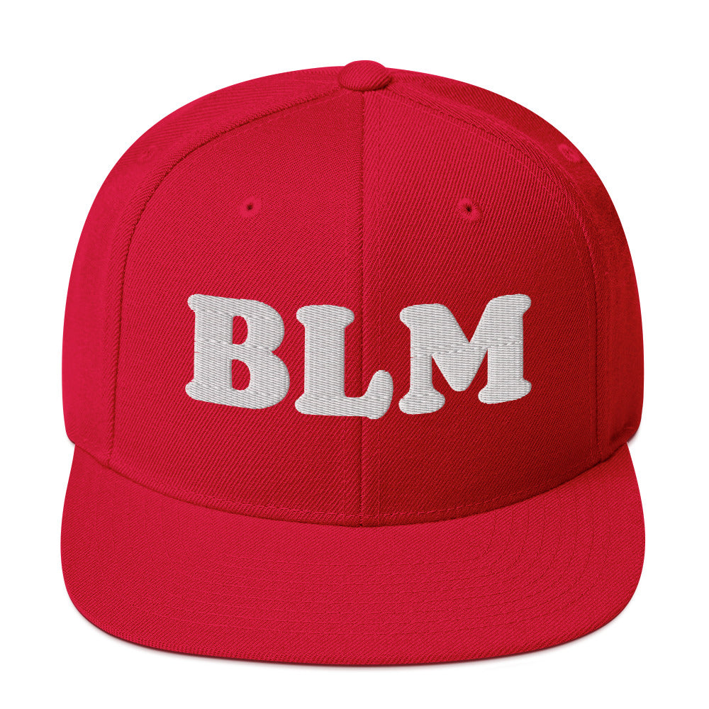 Red snapback hat with raised embroidered “BLM” lettering in light thread, bold statement design with structured crown and flat brim.