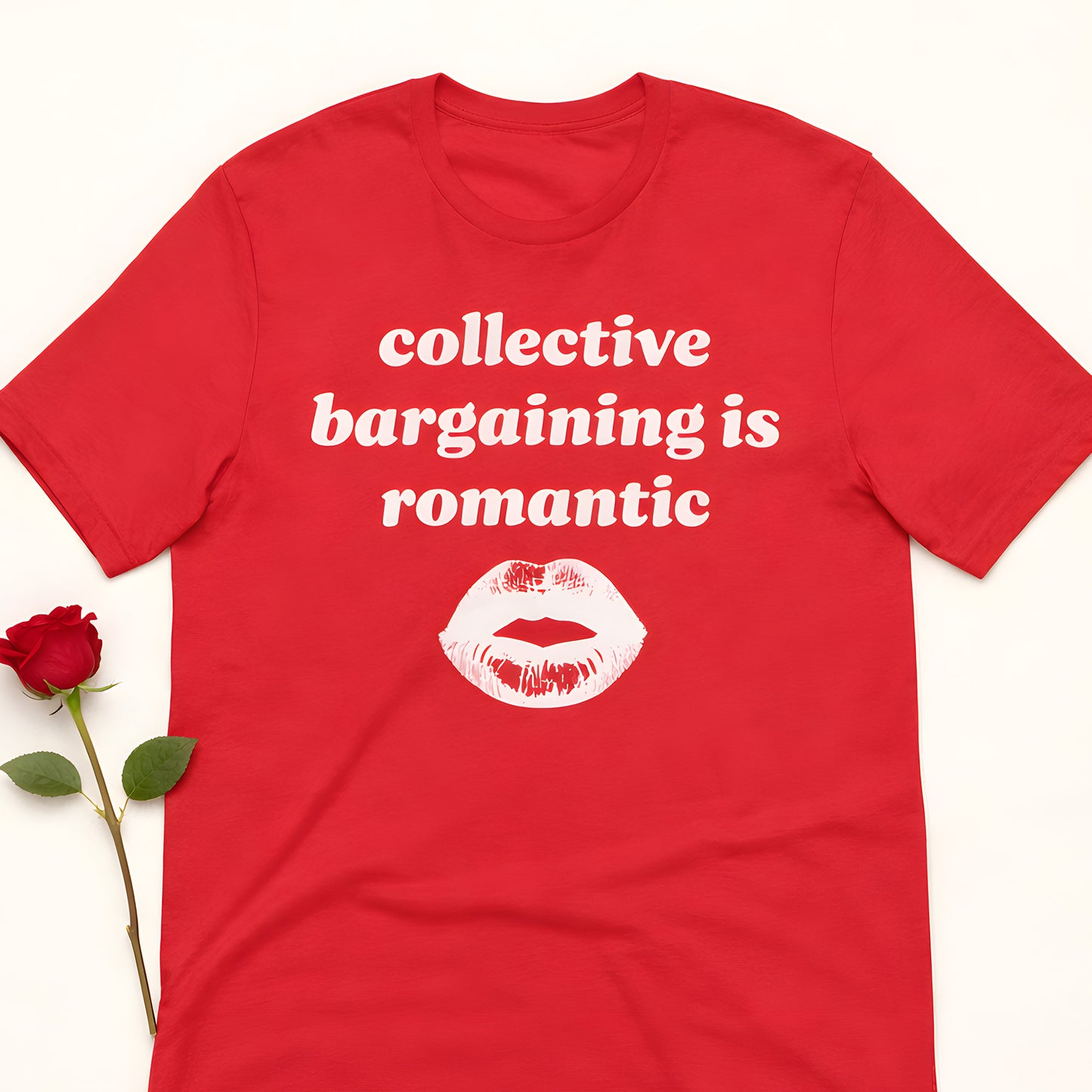 Unisex political t-shirt featuring bold white typography and lip graphic with the phrase “collective bargaining is romantic” on red fabric, styled as progressive labor rights apparel.