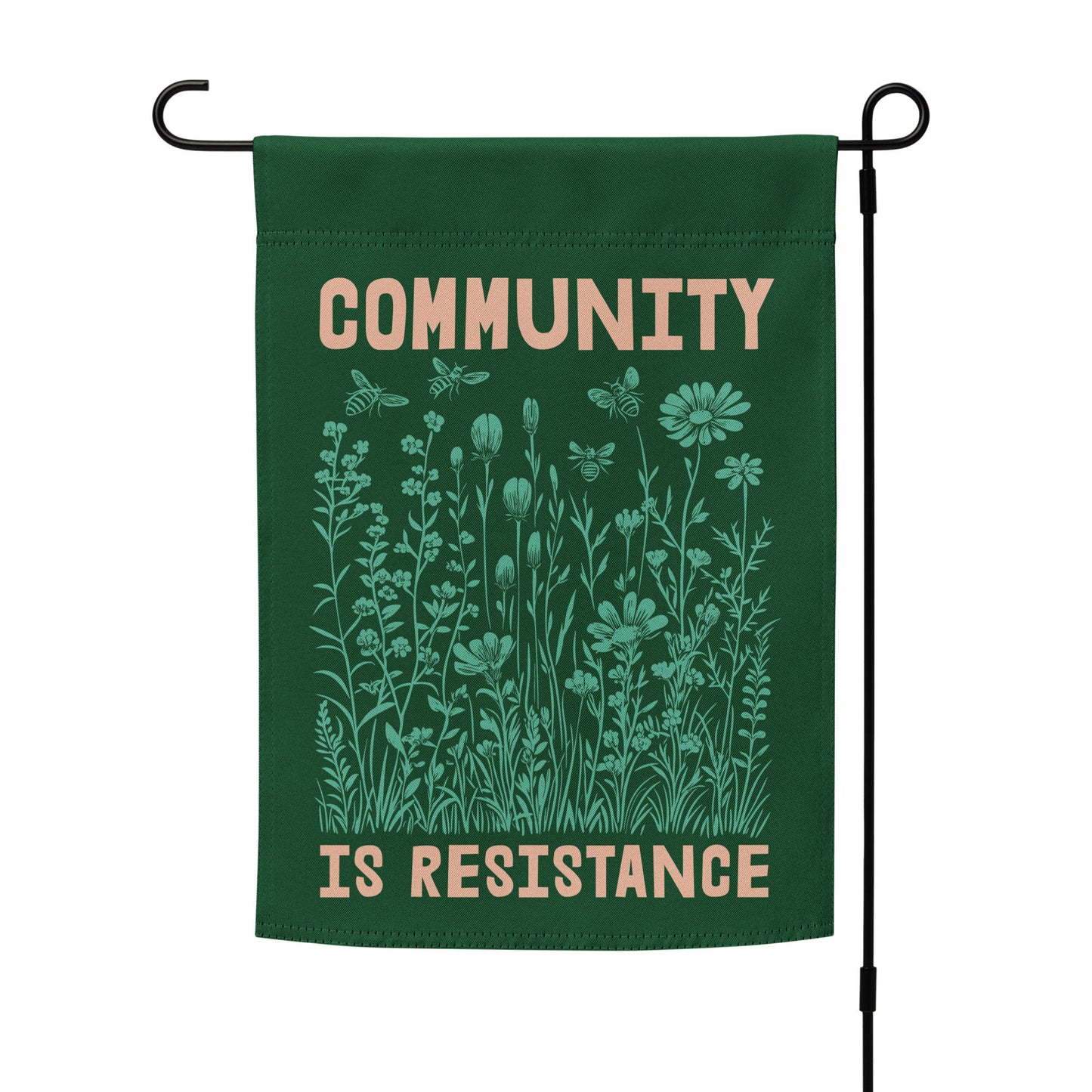 Forest green Community Is Resistance garden flag shown on a black metal stand. The delicate botanical illustration evokes unity, resilience, and connection.