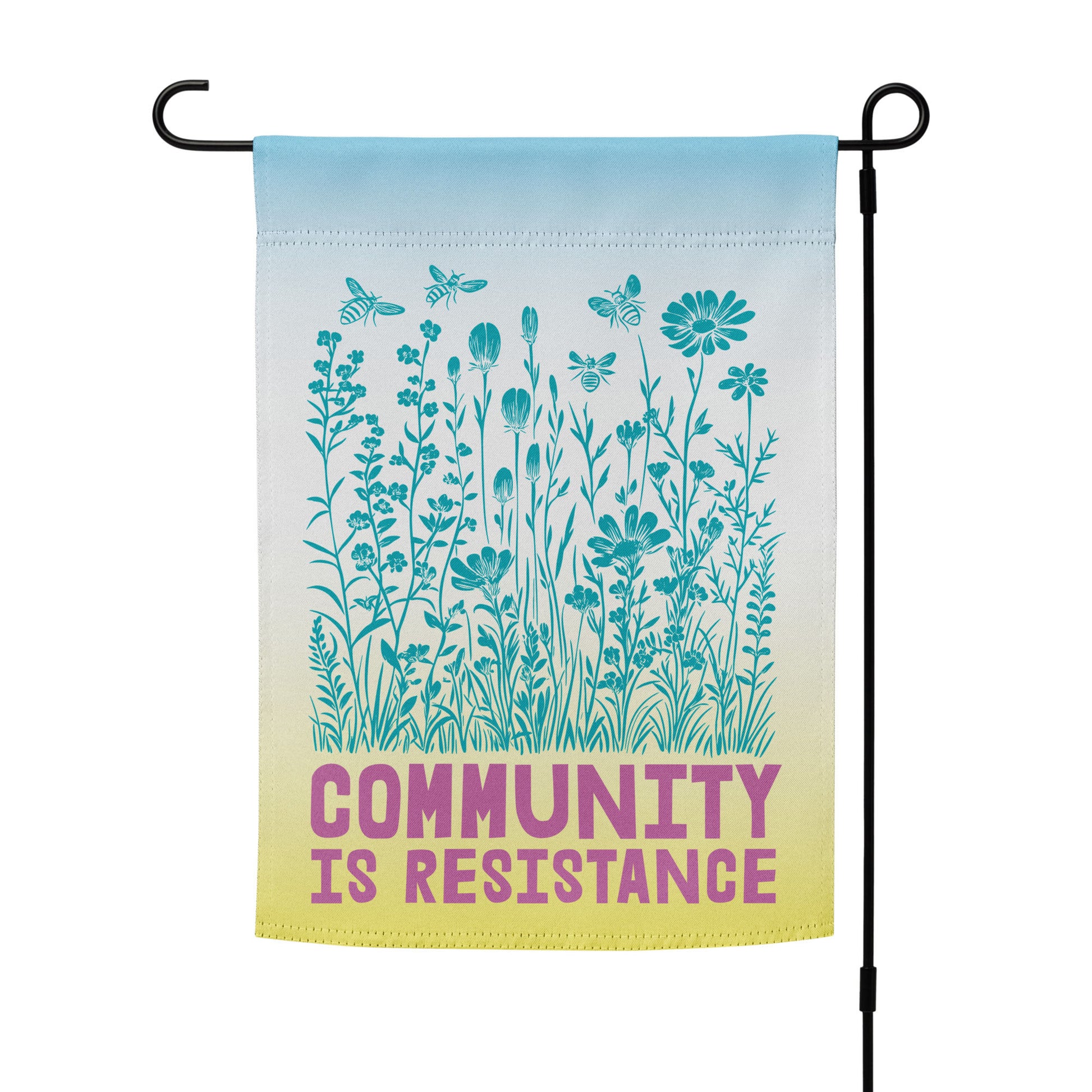 Full view of the Community Is Resistance garden flag in blue-to-yellow gradient tones, printed with fine wildflower illustrations and bold magenta lettering. A symbol of unity through compassion and action.
