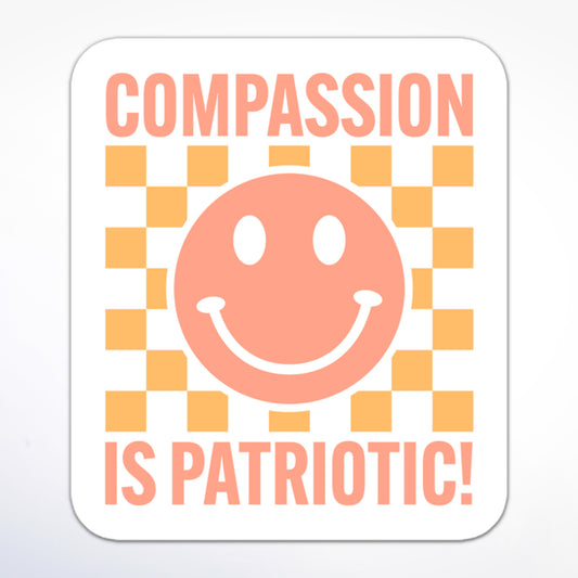 Minimalist social justice sticker featuring a smiley face and block text “Compassion is Patriotic!” in an orange gradient on a whitet background.