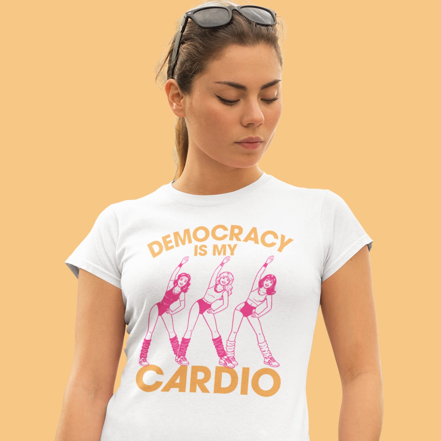 Model wearing white women’s relaxed t-shirt displaying retro pink dancer artwork with phrase “DEMOCRACY IS MY CARDIO.”