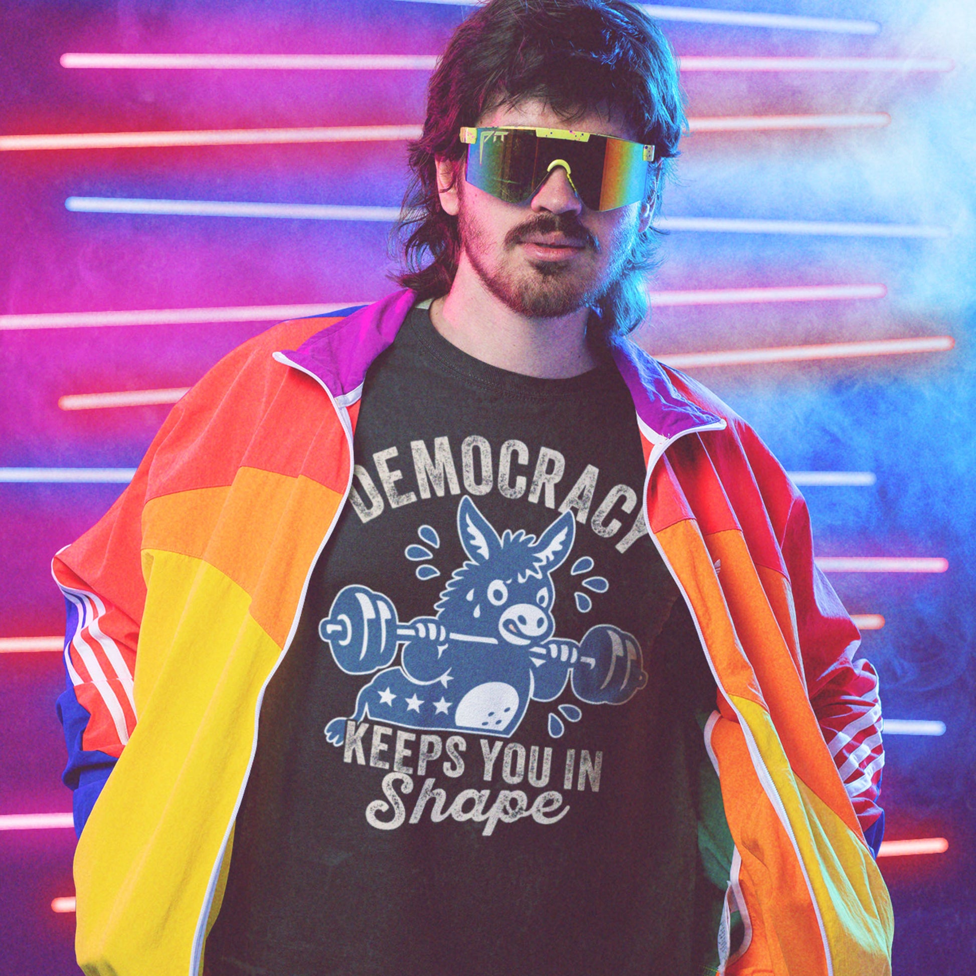 Blue Wave USA unisex T-shirt worn with rainbow jacket and sunglasses, featuring a weightlifting donkey graphic and democracy fitness slogan in retro activist style.