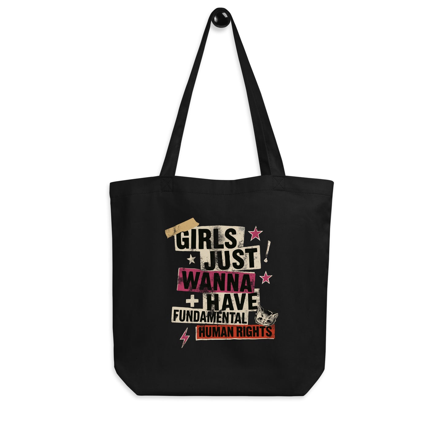 Black “Girls Just Wanna Have Fundamental Human Rights” tote bag hanging by its handles. Punk collage feminist design with taped lettering and distressed textures by Blue Wave USA.