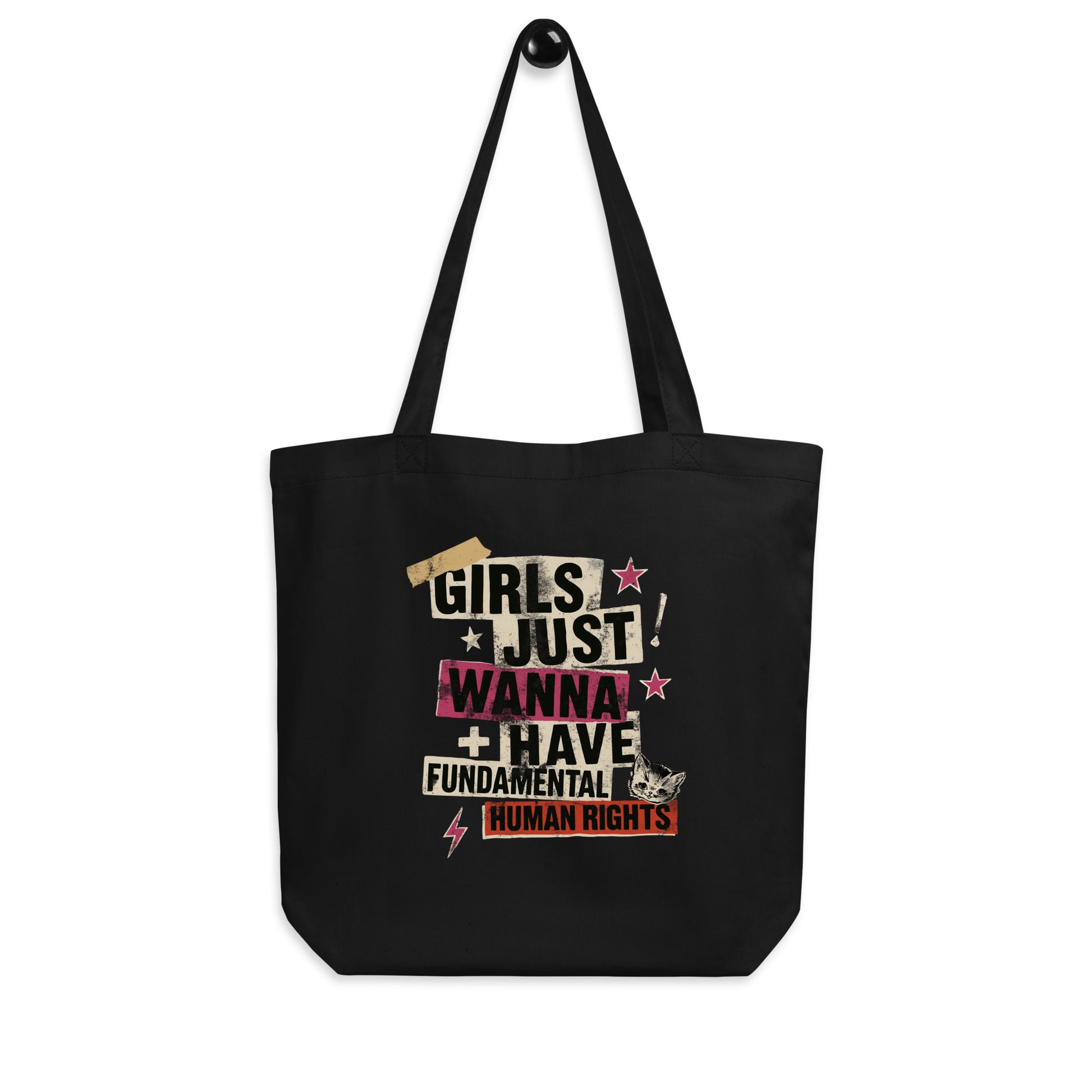 Black “Girls Just Wanna Have Fundamental Human Rights” tote bag hanging by its handles. Punk collage feminist design with taped lettering and distressed textures by Blue Wave USA.