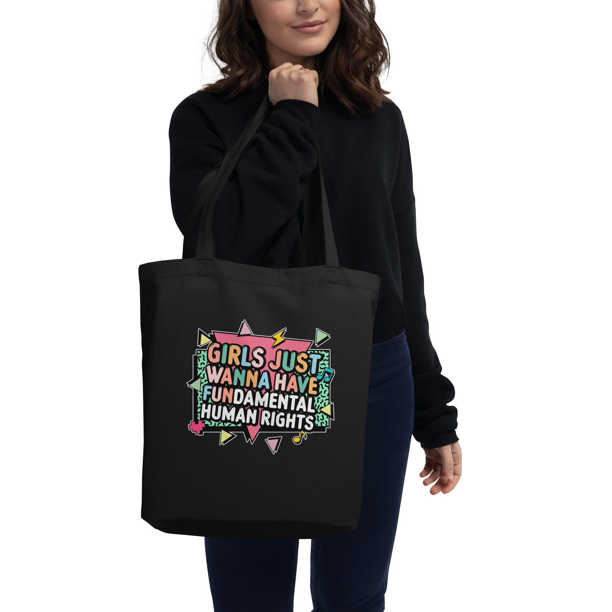 Model carrying the black “Girls Just Wanna Have Fundamental Human Rights” tote with 80s-style lettering and bright pastel details. Progressive feminist bag by Blue Wave USA.