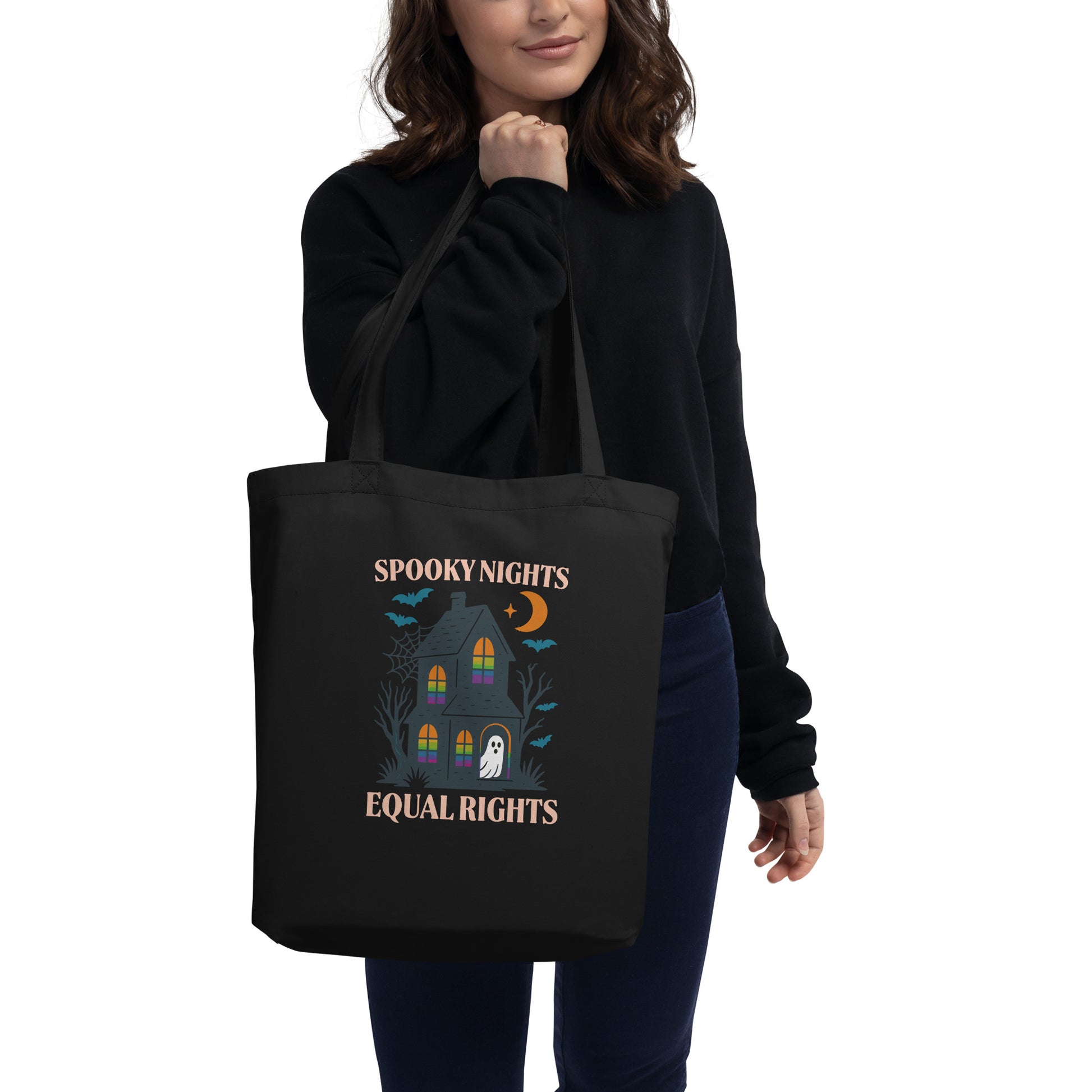 Model carrying the “Spooky Nights Equal Rights” Halloween tote bag featuring a haunted house and ghost design. Feminist eco bag for spooky season by Blue Wave USA.
