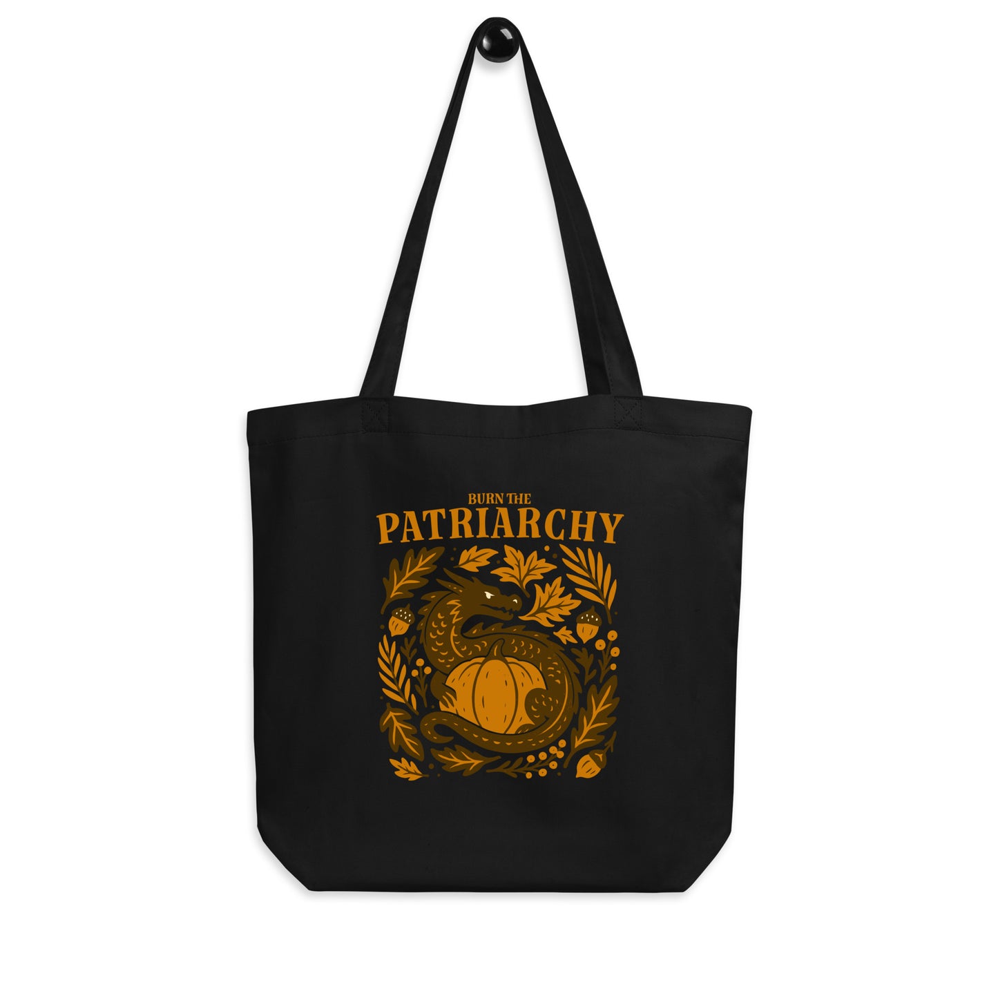 Black eco tote bag featuring a golden dragon curled around a pumpkin surrounded by autumn leaves with the phrase “Burn the Patriarchy.” Bold feminist tote by Blue Wave USA.