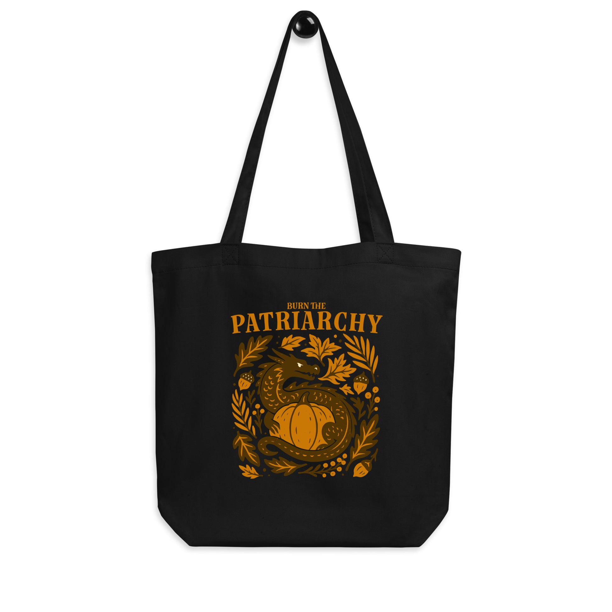 Black eco tote bag featuring a golden dragon curled around a pumpkin surrounded by autumn leaves with the phrase “Burn the Patriarchy.” Bold feminist tote by Blue Wave USA.